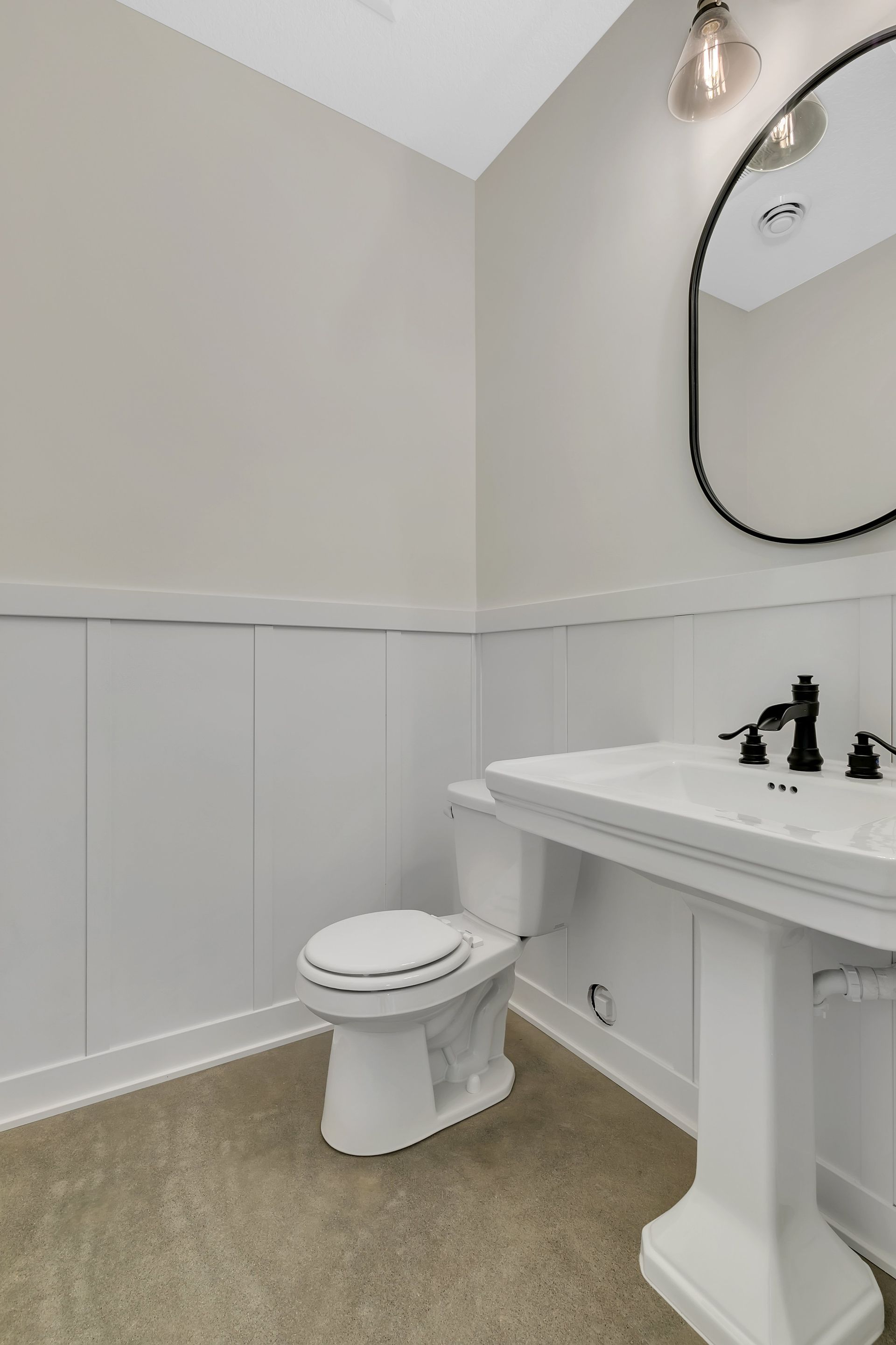 A bathroom with a toilet , sink and mirror.