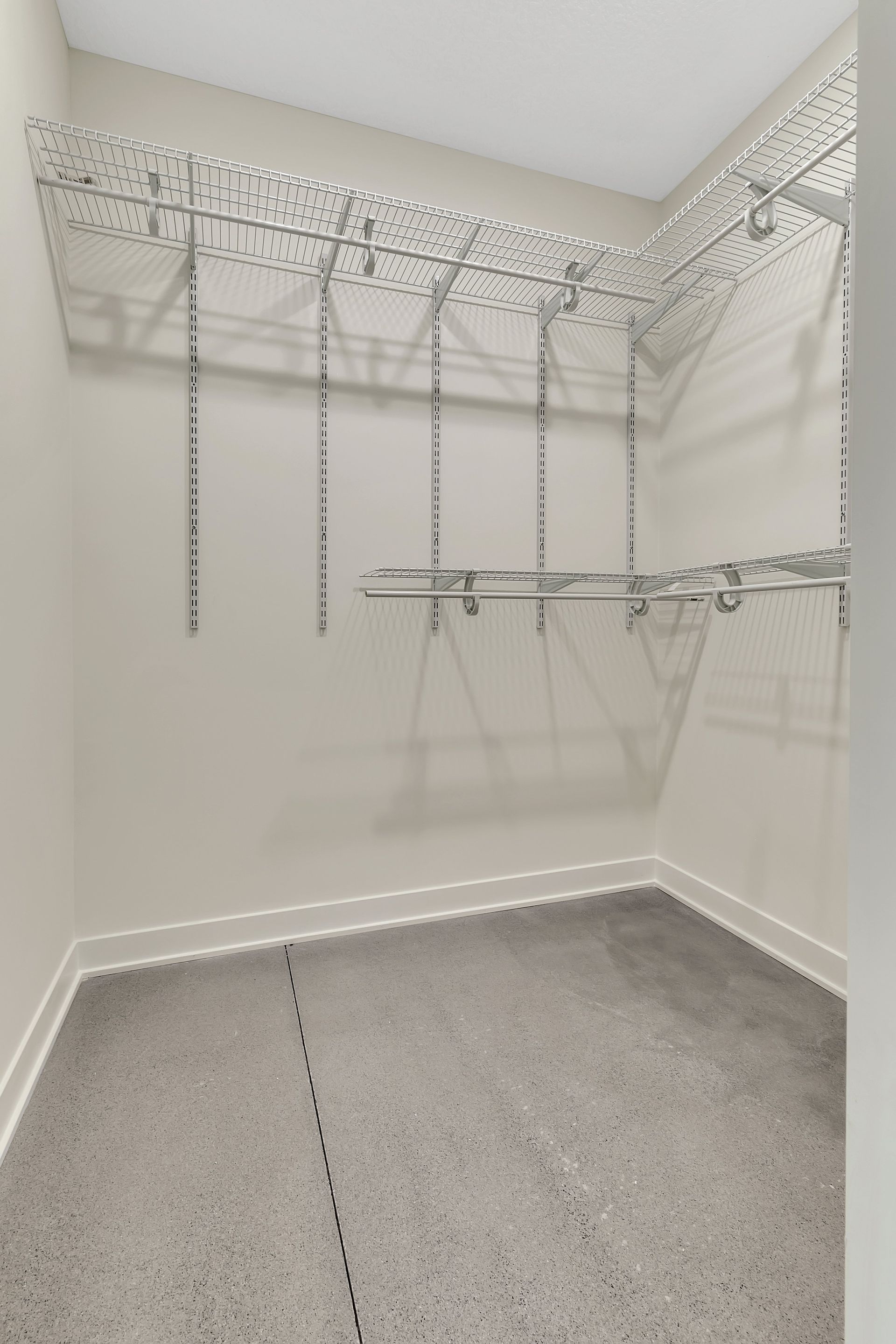 An empty walk in closet with lots of shelves and racks.
