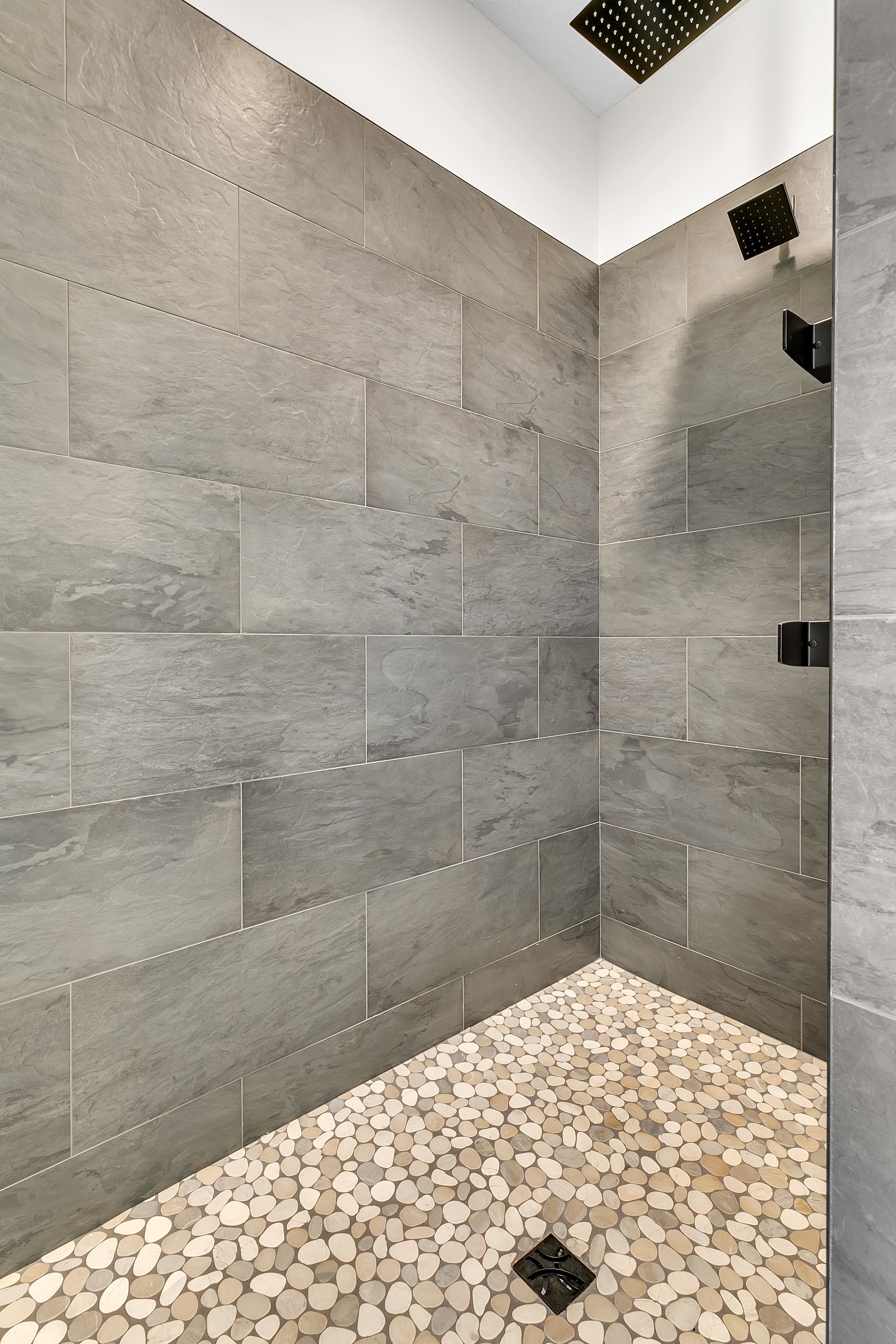 A shower with a tiled wall and a mosaic floor.