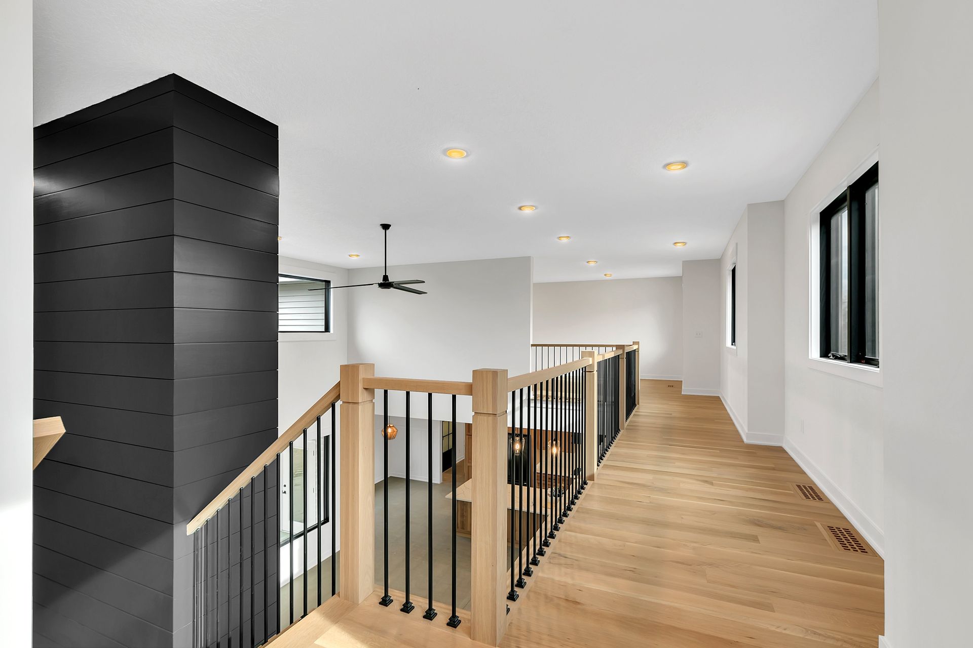 A hallway with a wooden floor and a black railing