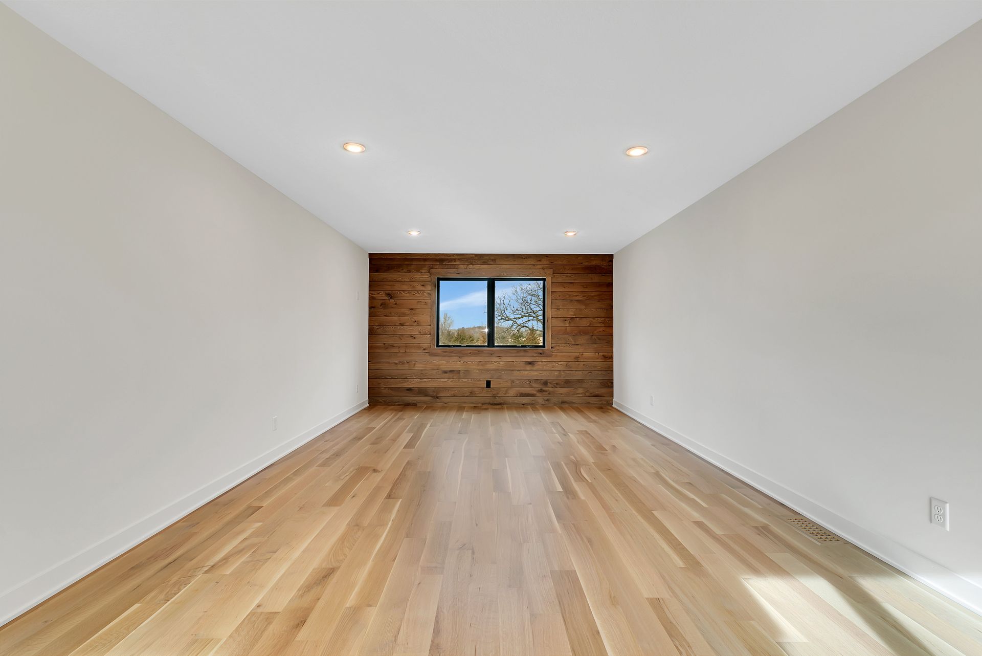 An empty room with hardwood floors and a wooden wall.