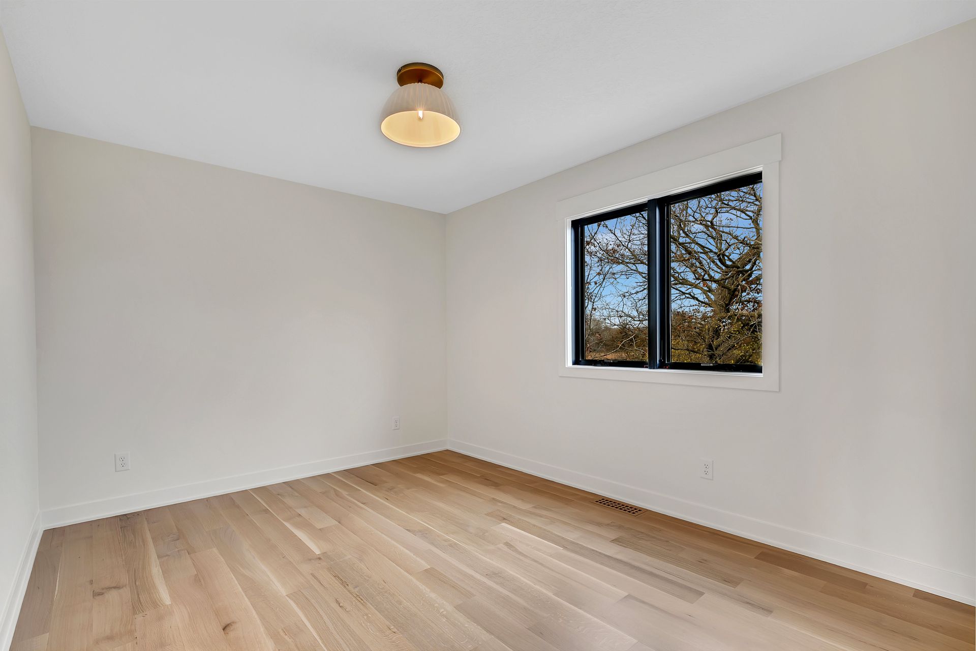 An empty room with hardwood floors and a window.
