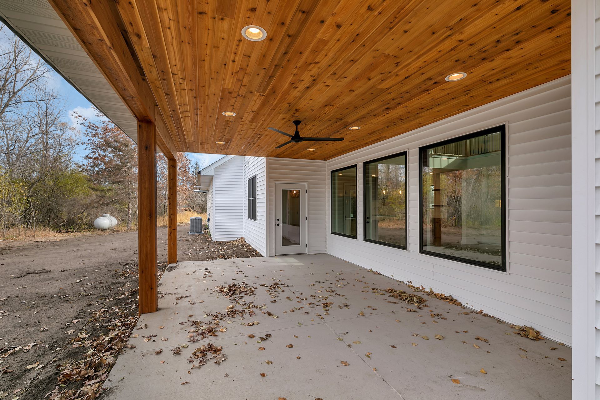 A large covered porch with a wooden ceiling and a ceiling fan.