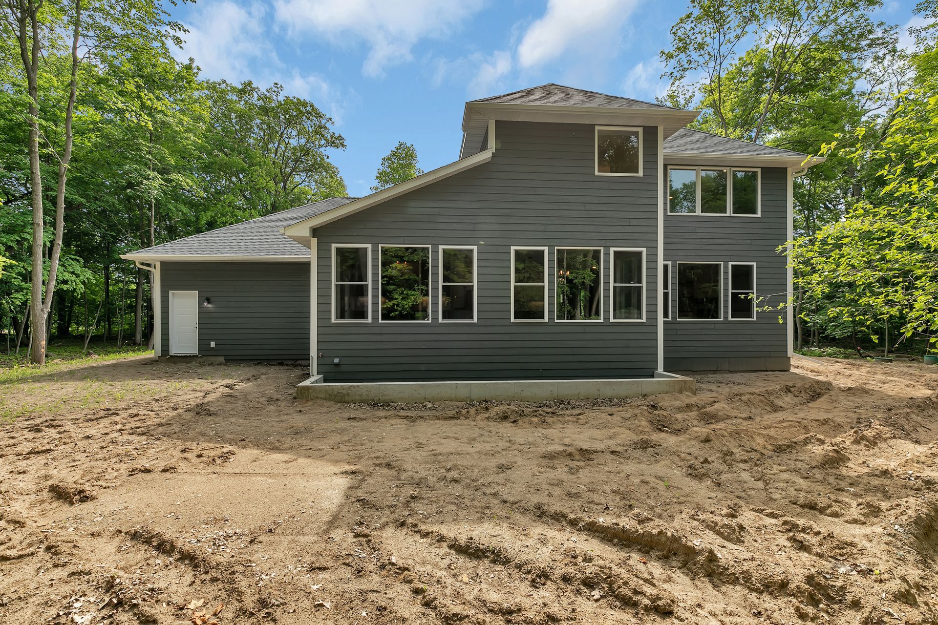 A large house with a lot of windows is sitting in the middle of a dirt field.