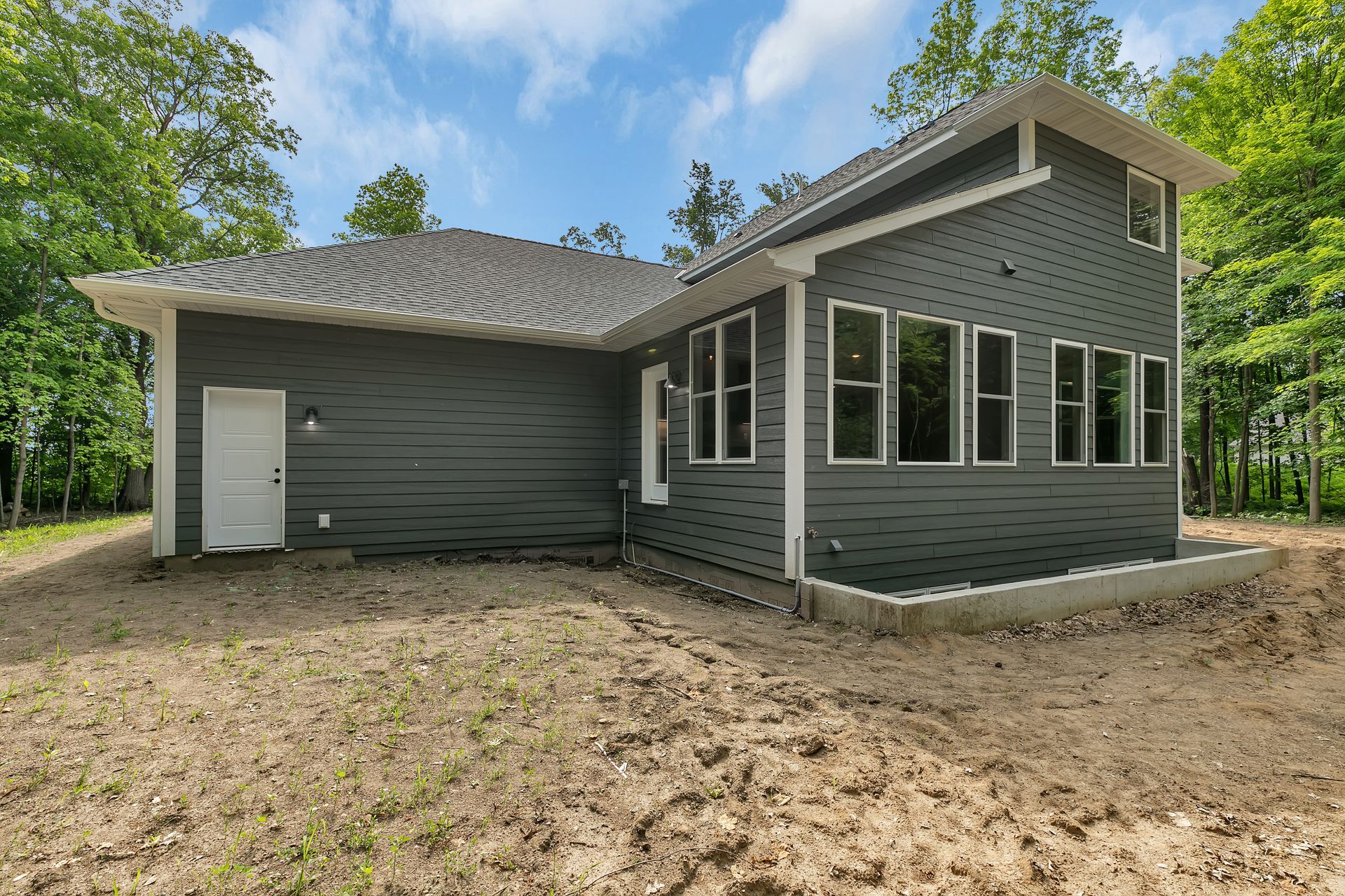 A house with a lot of windows is sitting in the middle of a dirt field.