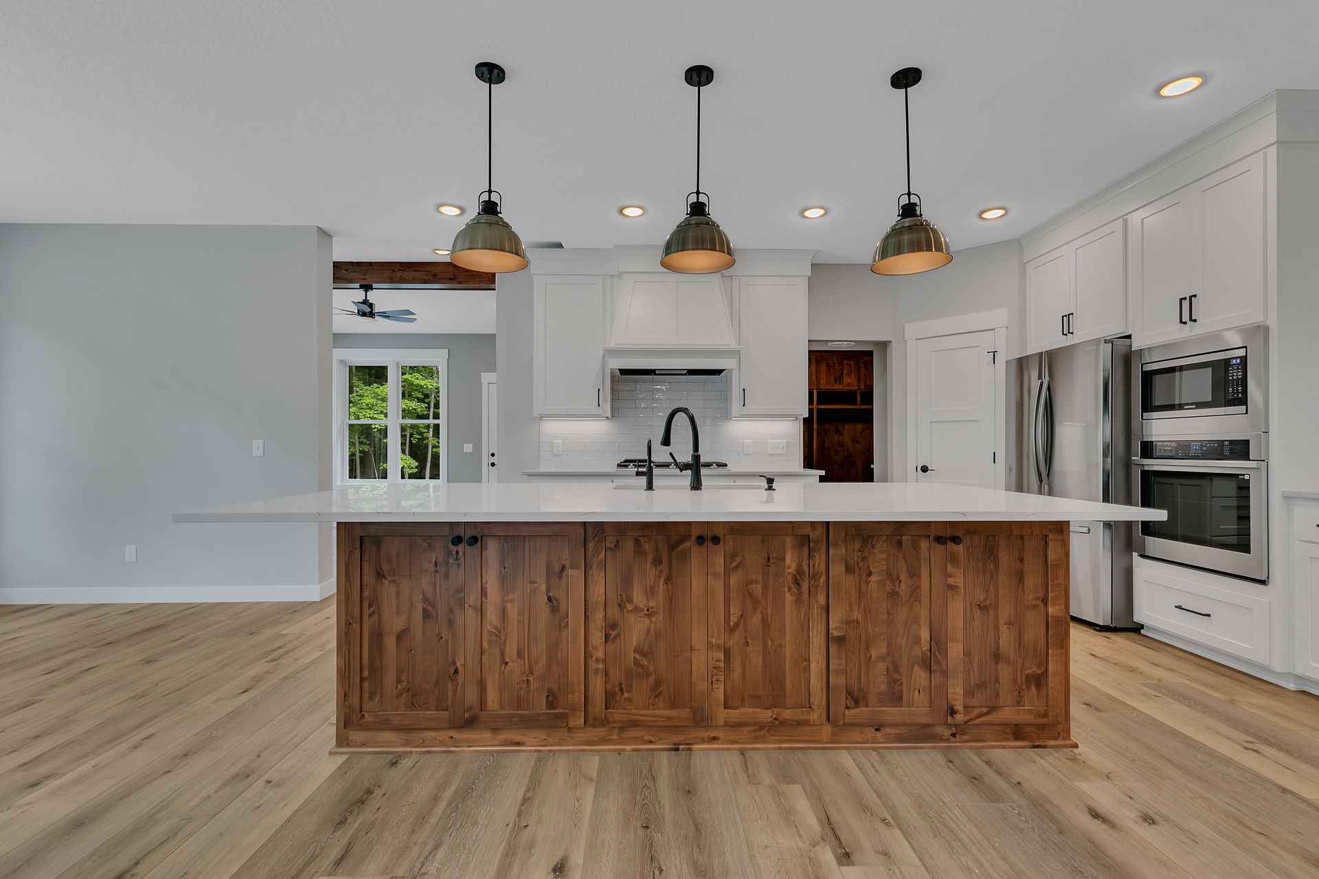 A kitchen with a large island , white cabinets , stainless steel appliances and hardwood floors.