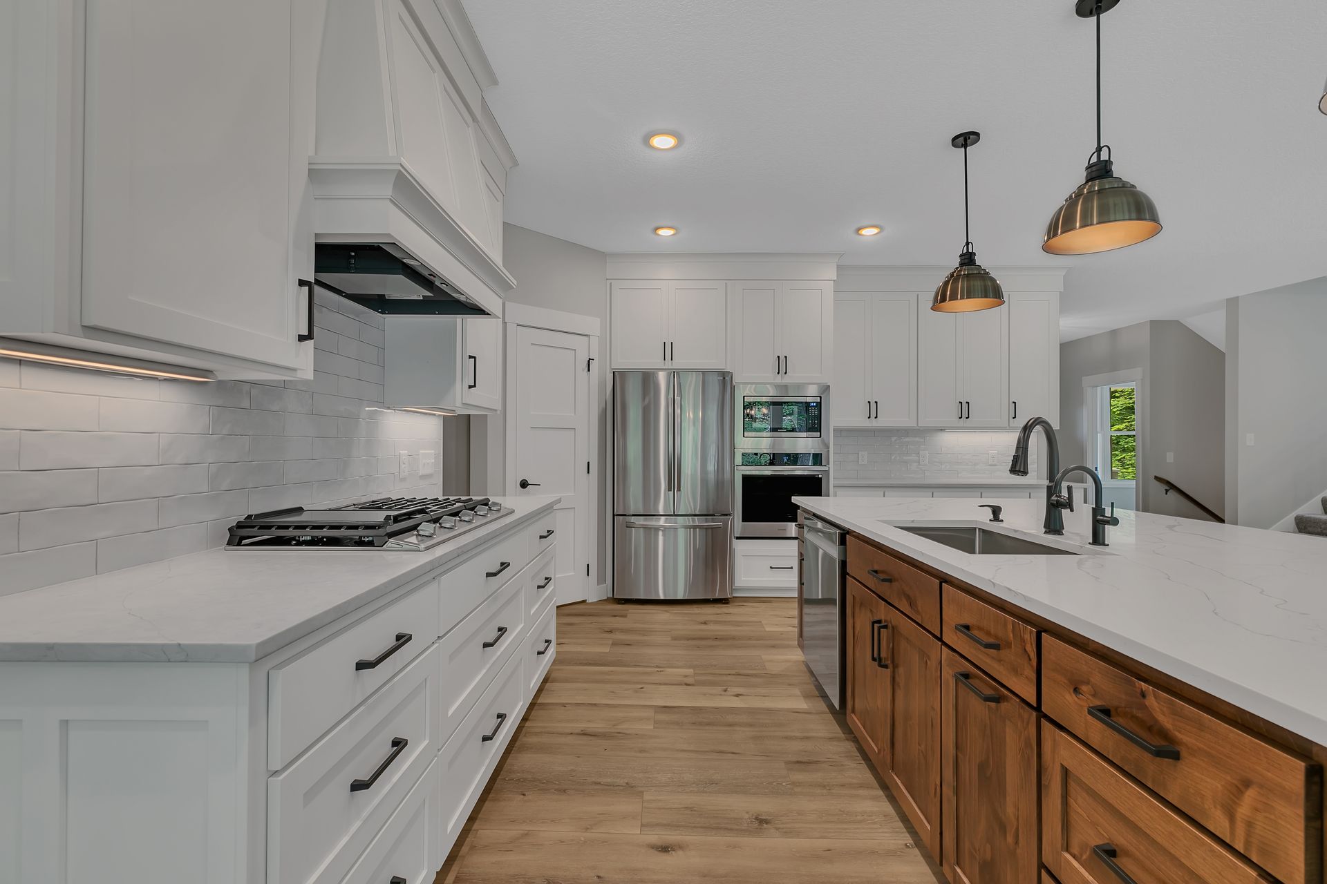 A kitchen with white cabinets and wooden cabinets and stainless steel appliances.