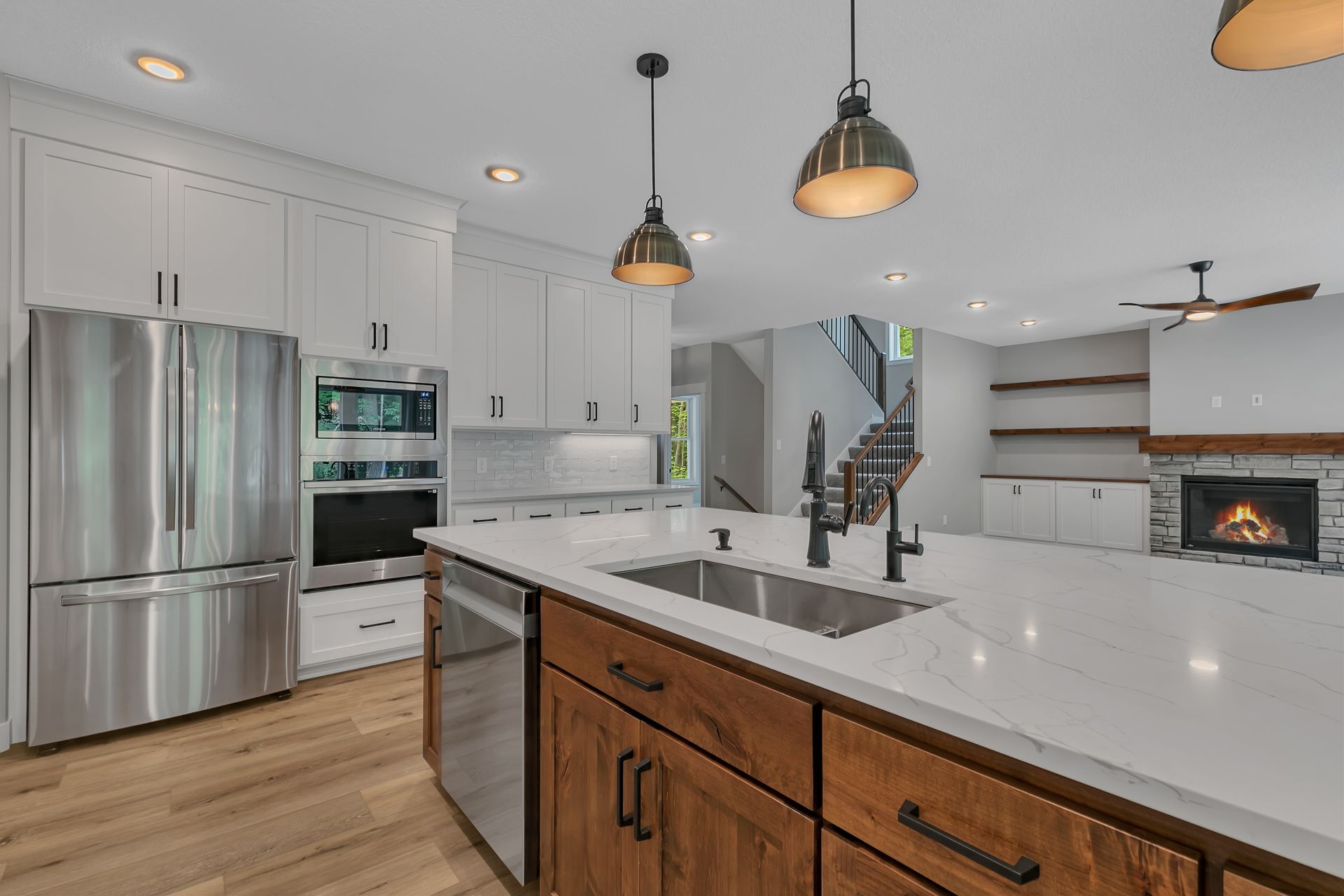 A kitchen with stainless steel appliances , wooden cabinets , a sink and a refrigerator.