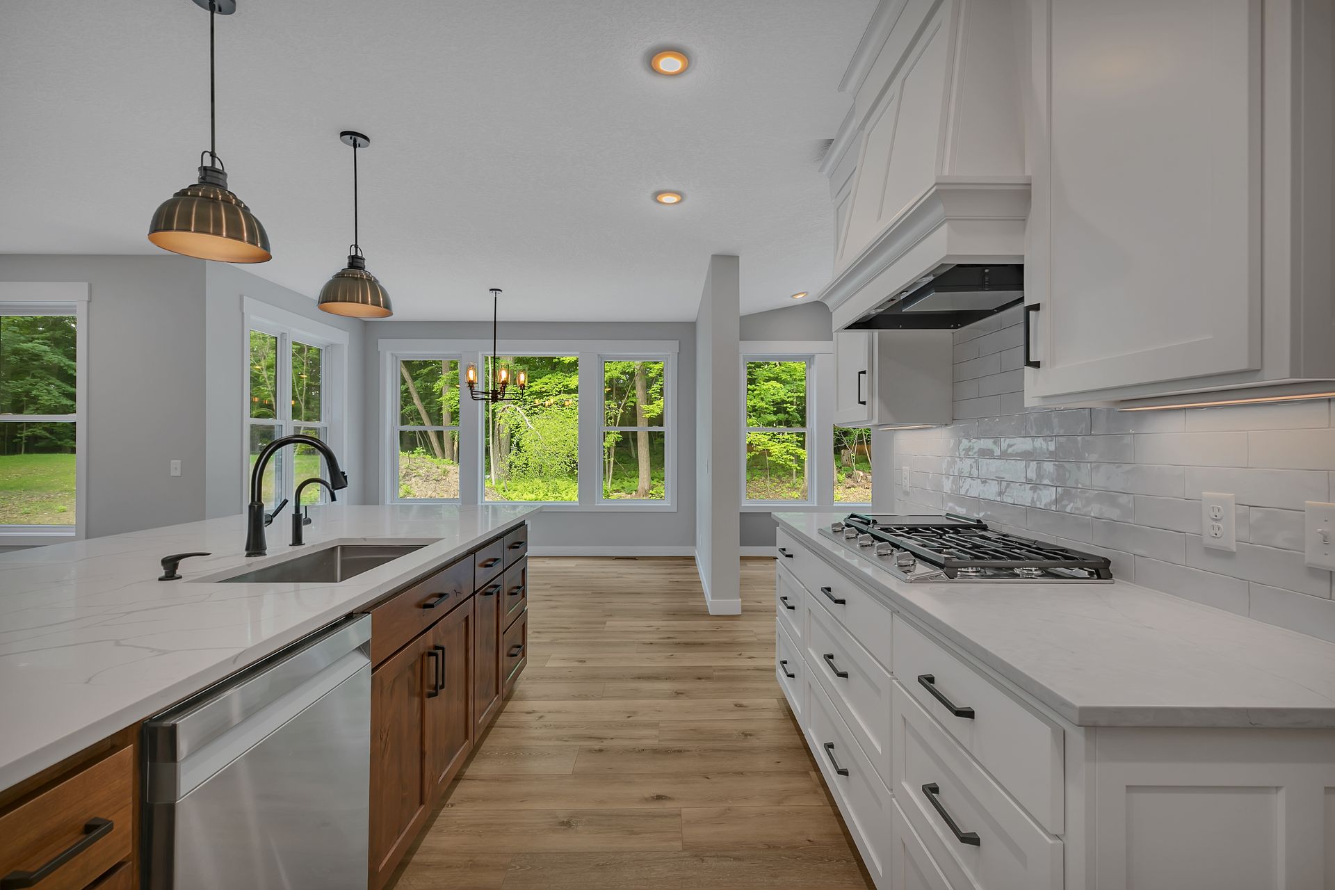 A kitchen with white cabinets , a stove , a sink and a dishwasher.