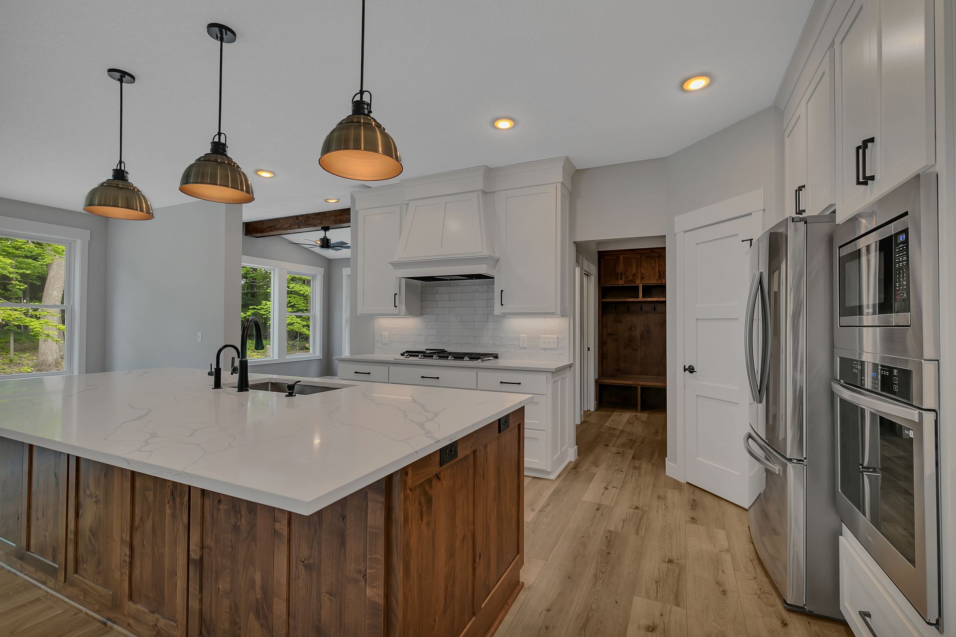 A kitchen with a large island , white cabinets , stainless steel appliances , and hardwood floors.