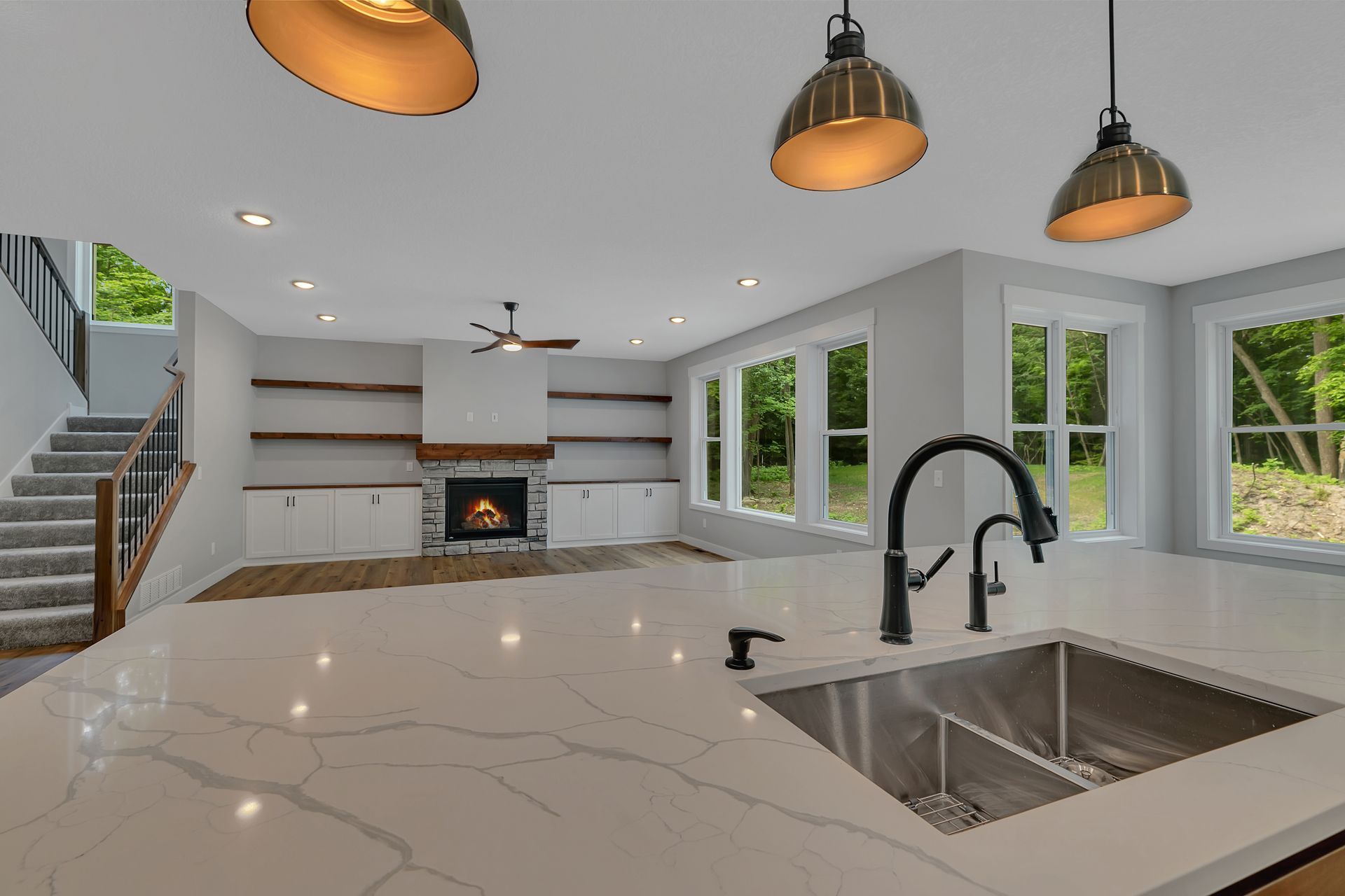 A kitchen with a sink and a fireplace in the background.