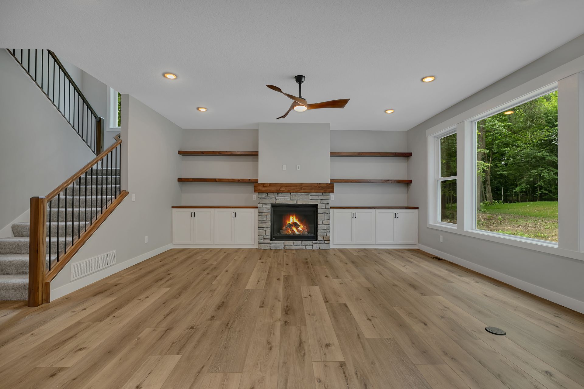 An empty living room with a fireplace and stairs.