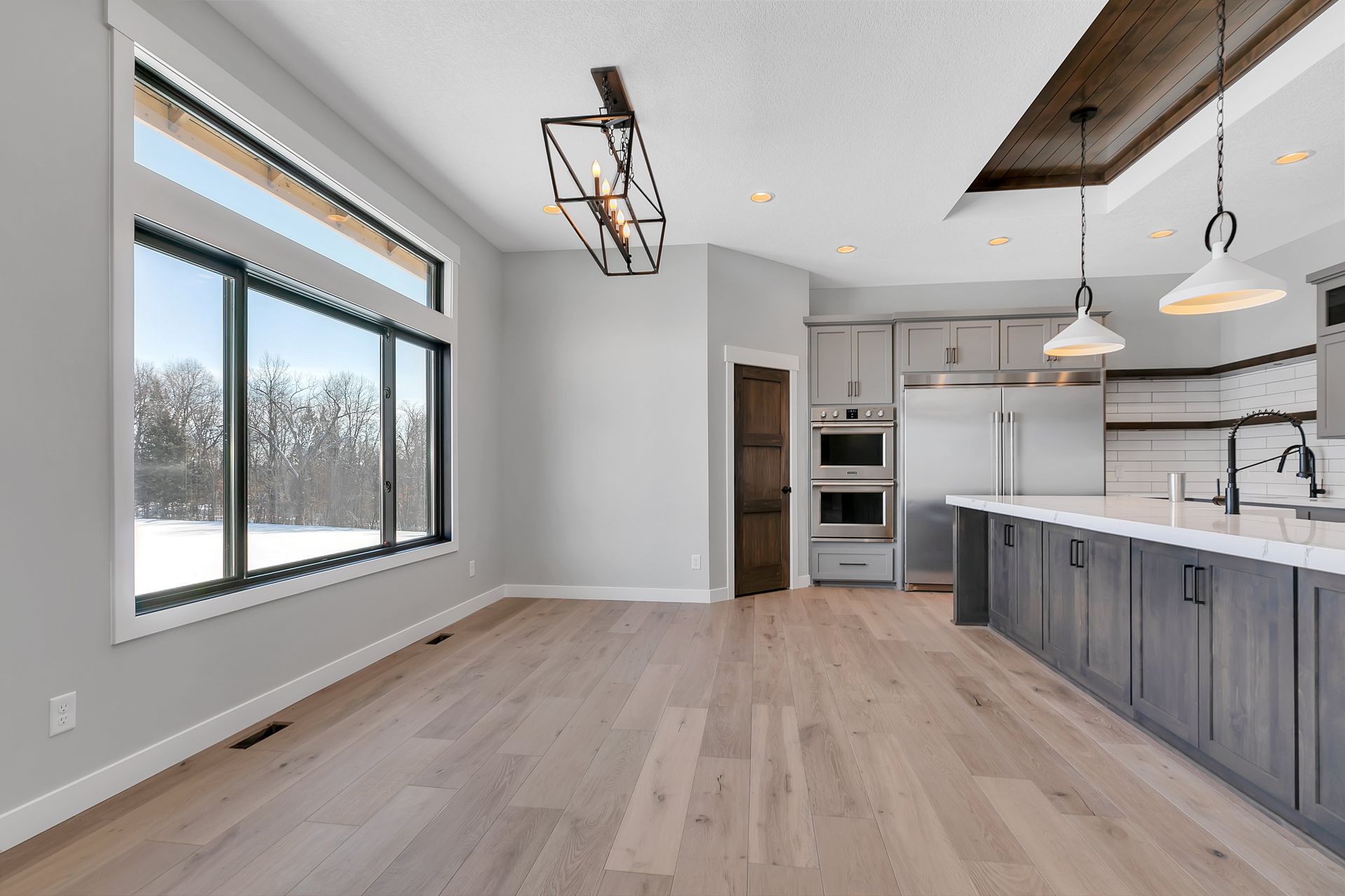 An empty kitchen with hardwood floors and stainless steel appliances