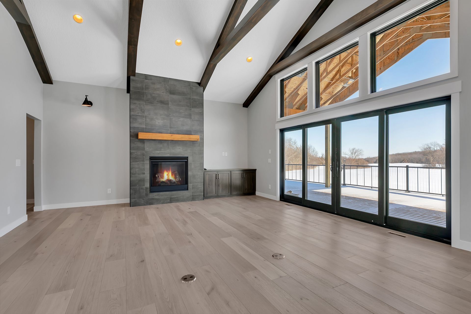 An empty living room with a fireplace and sliding glass doors.