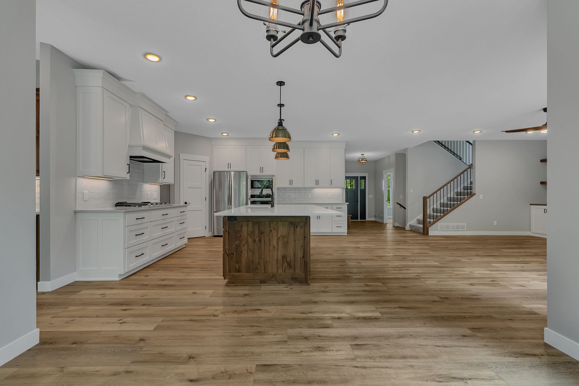 A kitchen with a large island in the middle of it and a chandelier hanging from the ceiling.