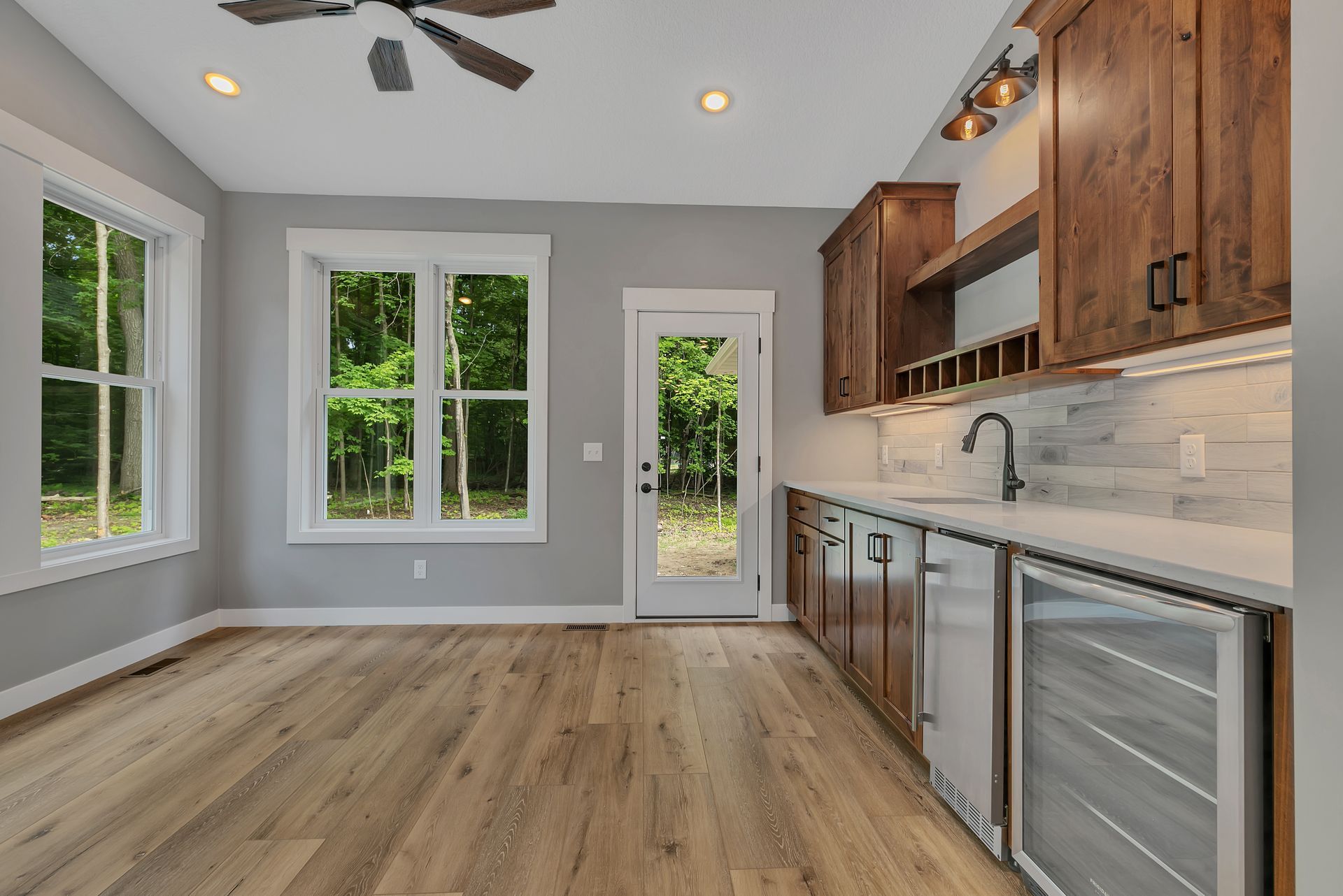 An empty kitchen with wooden cabinets and a ceiling fan.
