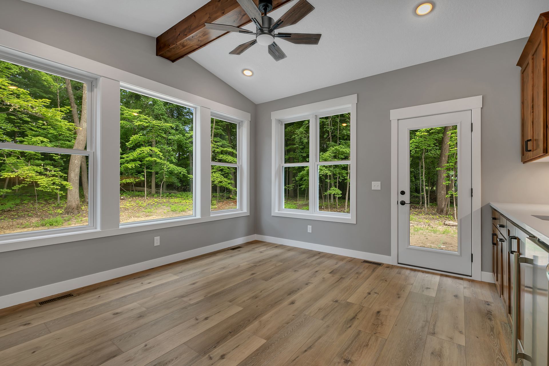 An empty room with a lot of windows and a ceiling fan.