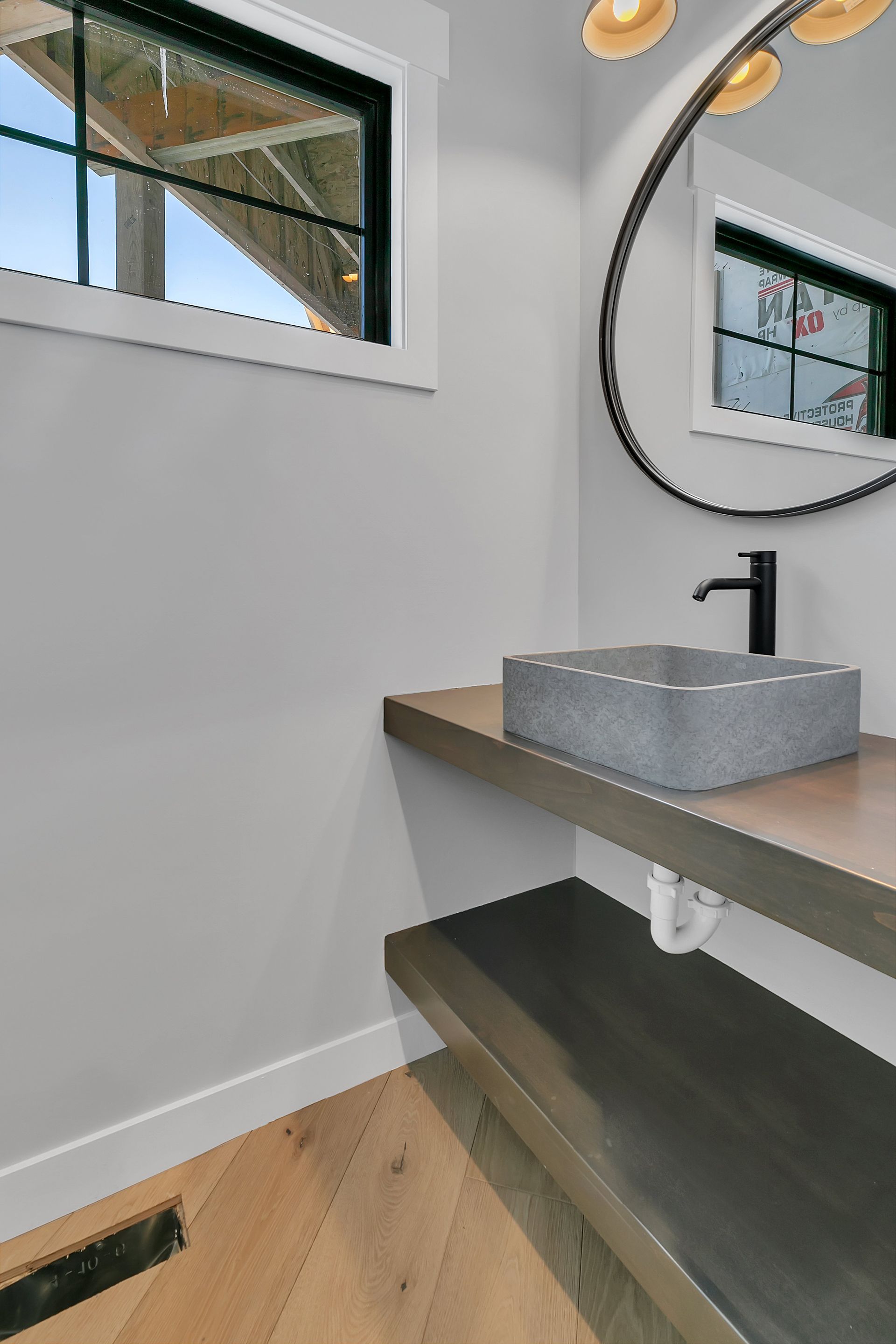 A bathroom with a sink , mirror and window.