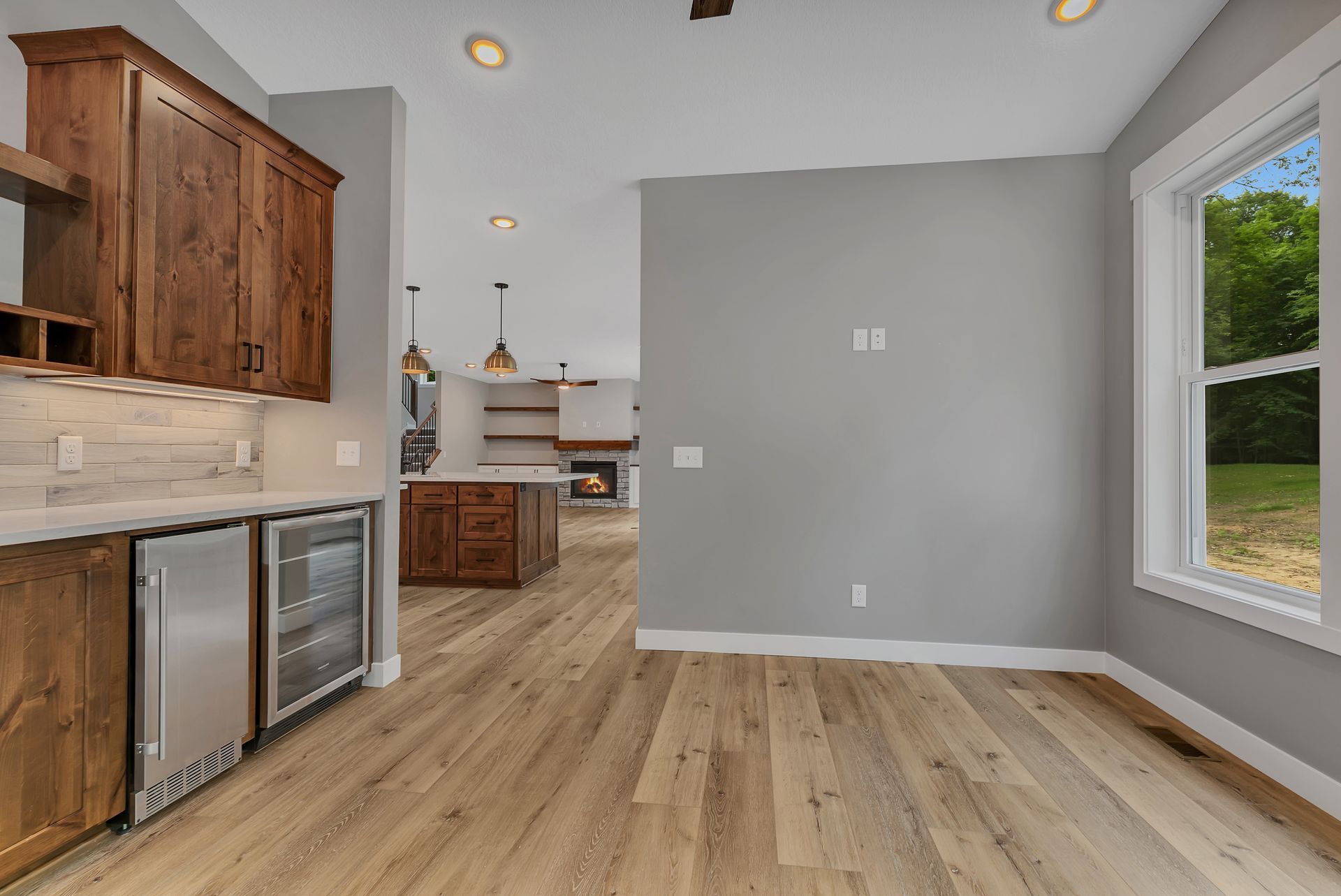 A kitchen with wooden cabinets , stainless steel appliances , a refrigerator and a window.