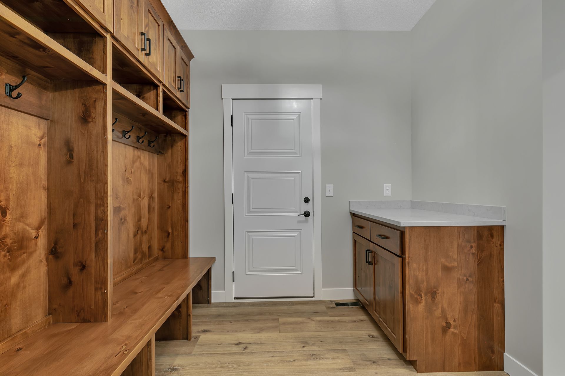 A mud room with wooden cabinets and a white door.