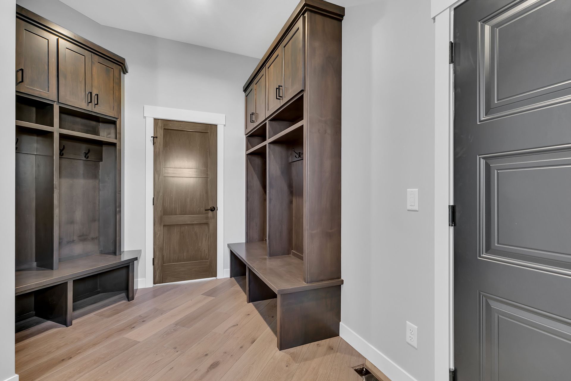 A hallway with wooden cabinets and a gray door.