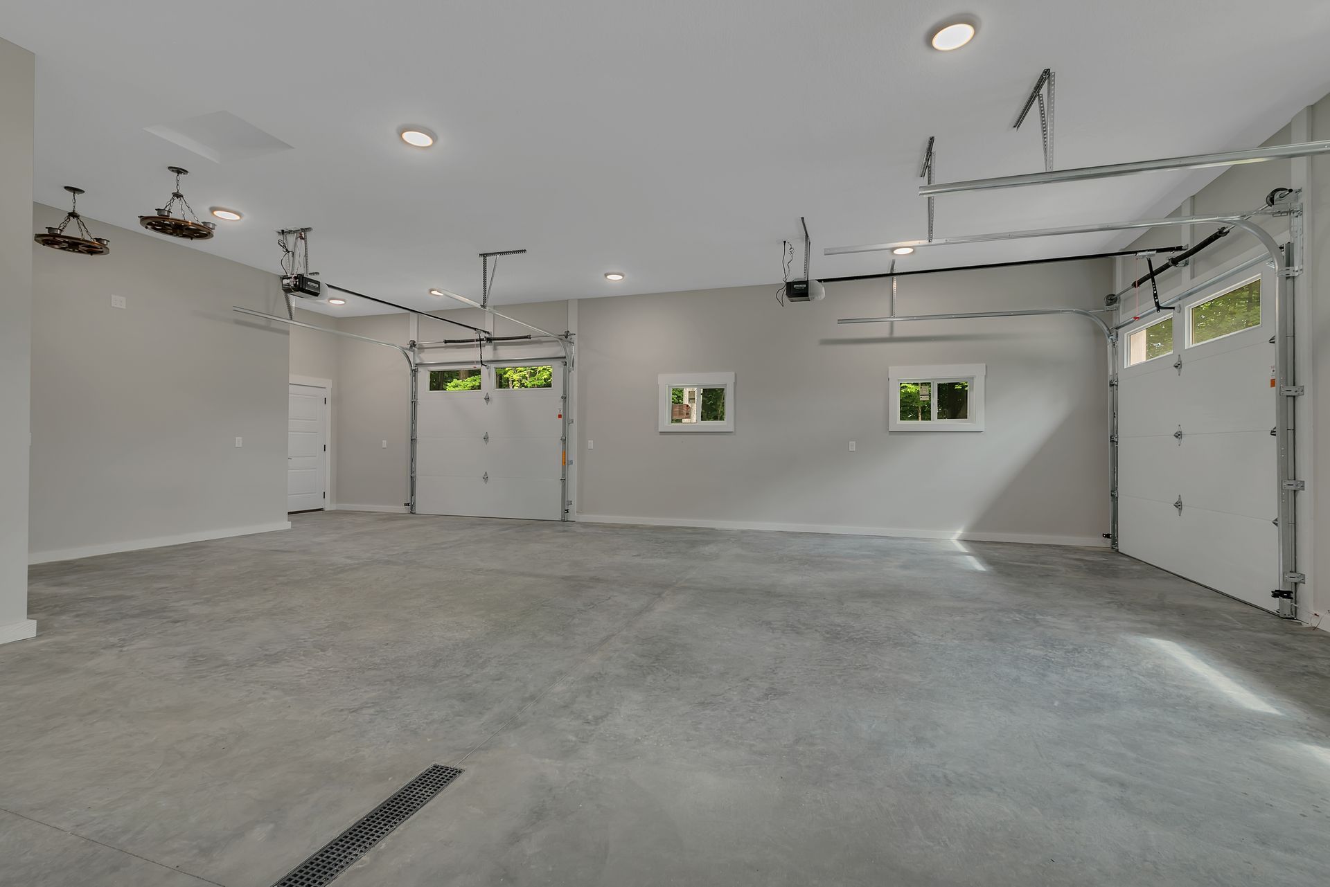 A large empty garage with two garage doors and a concrete floor.