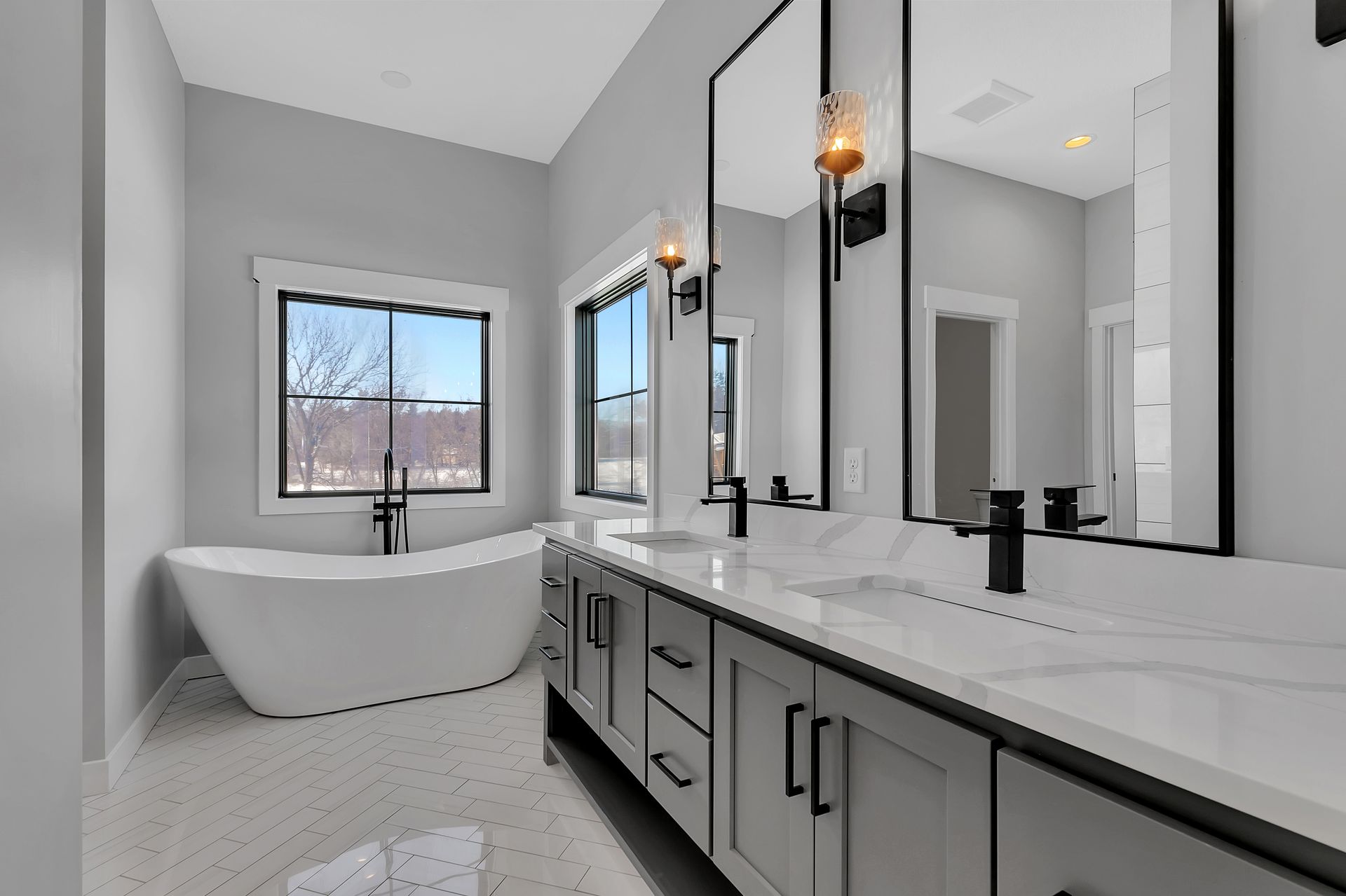 A bathroom with two sinks , a tub and two mirrors.