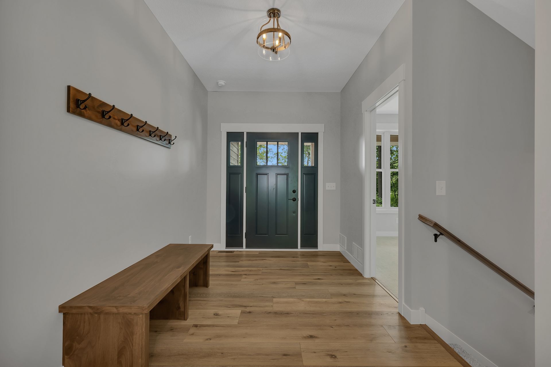 A hallway with a wooden bench and a black door.