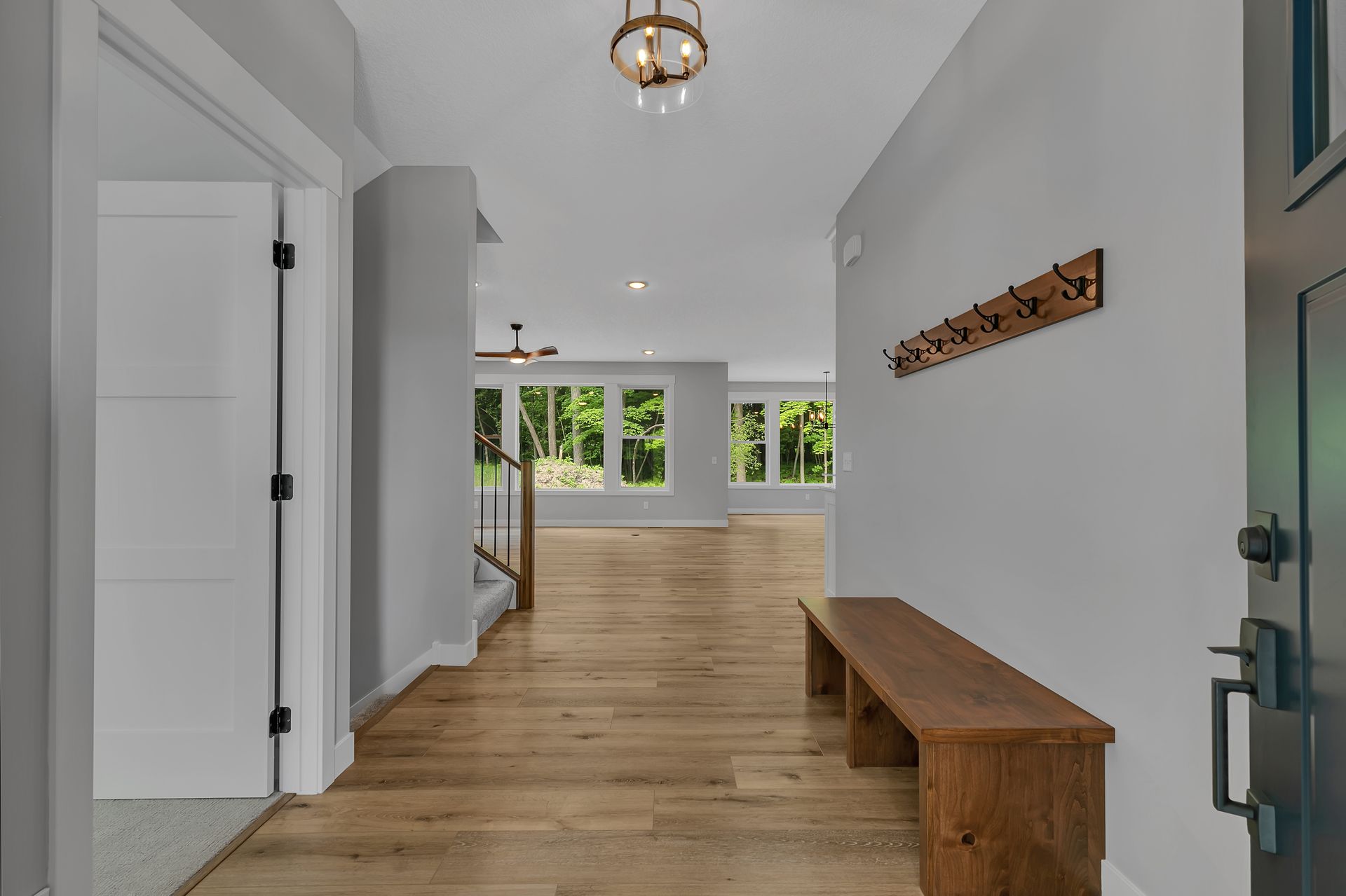 A hallway with a wooden bench and a coat rack on the wall.