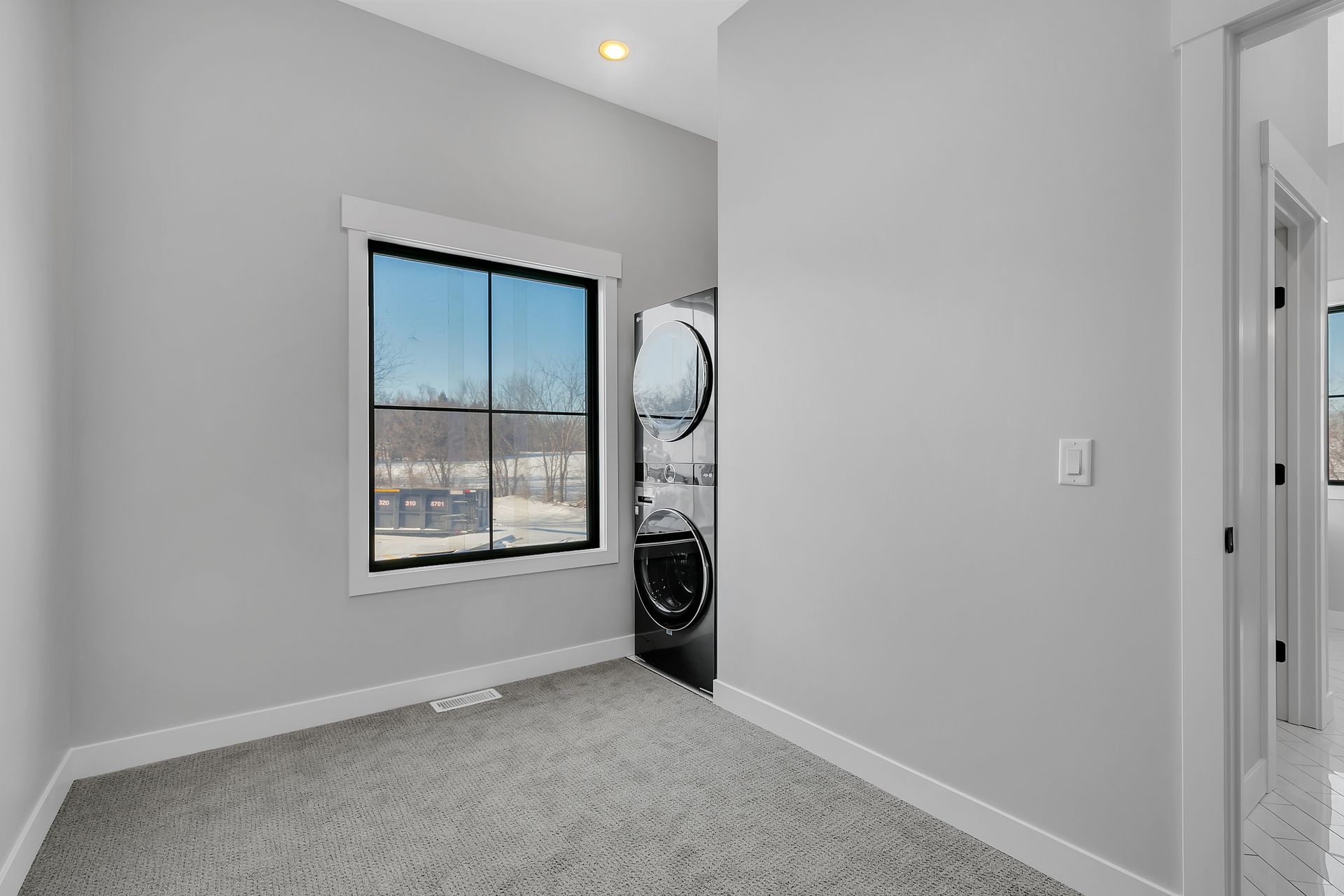 An empty room with a washer and dryer and a window.