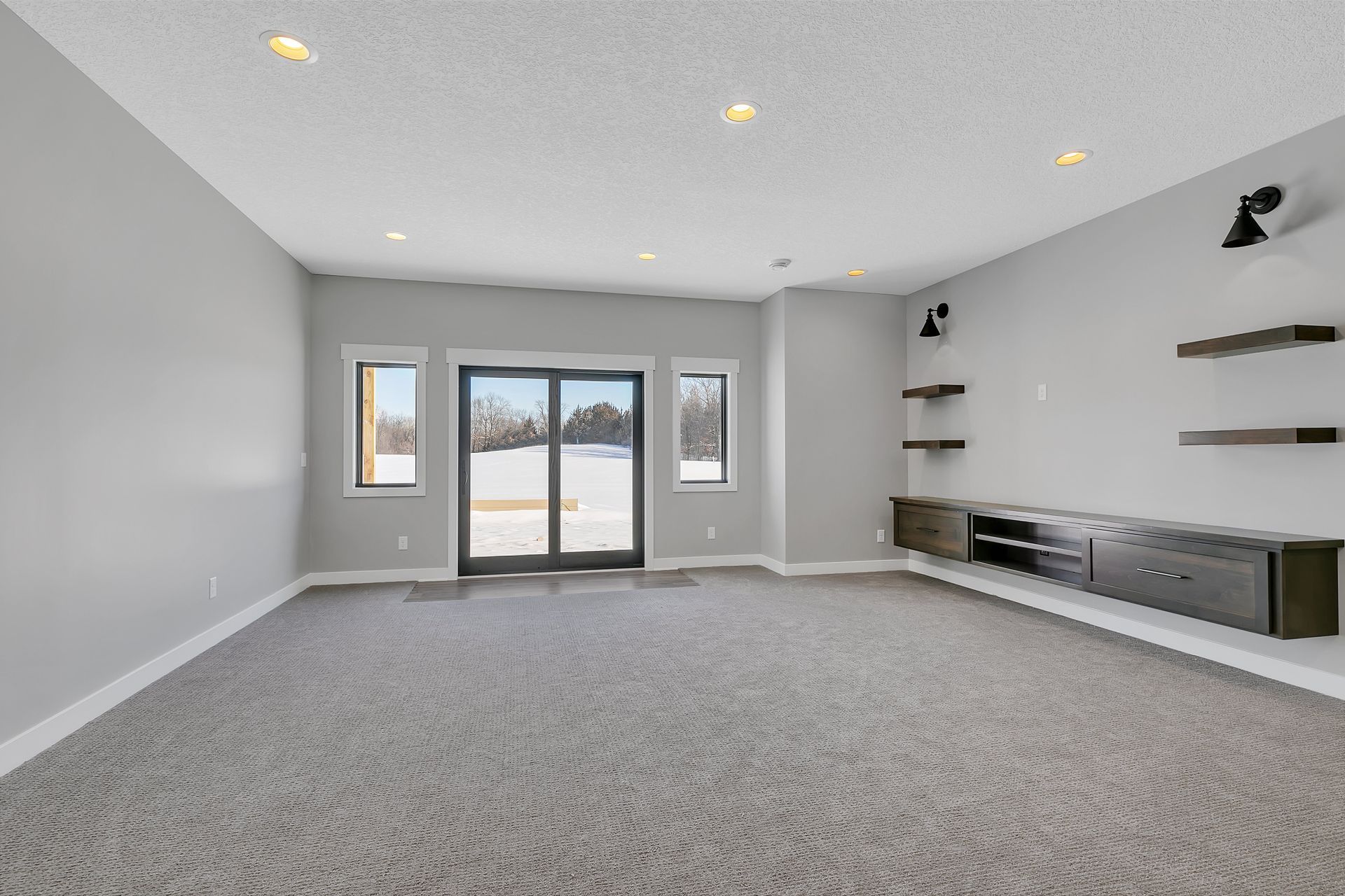 A large empty room with a carpeted floor and a sliding glass door.