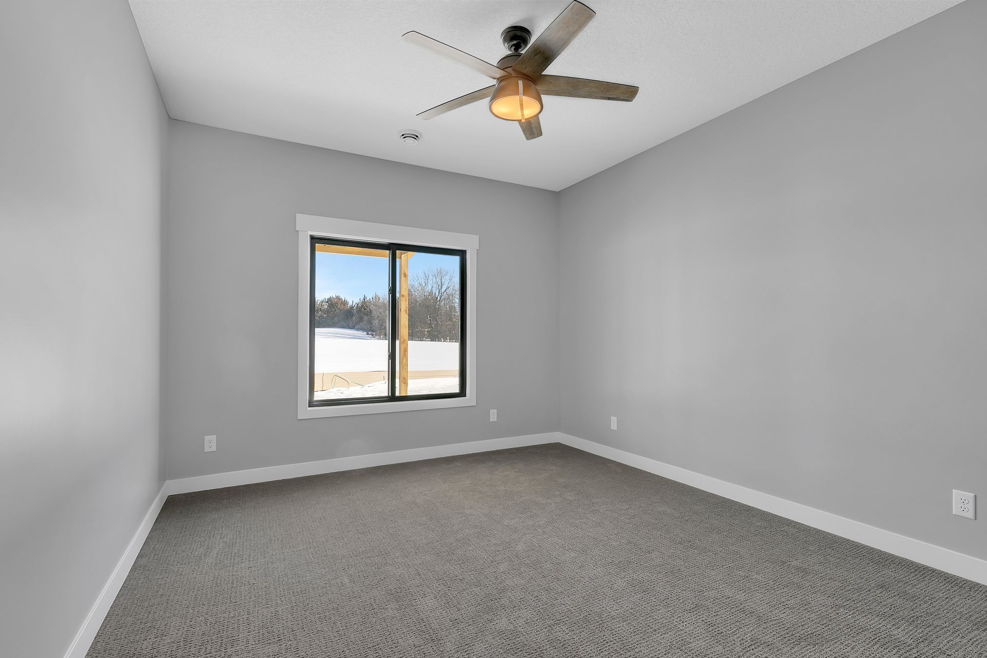 An empty bedroom with a ceiling fan and a window.