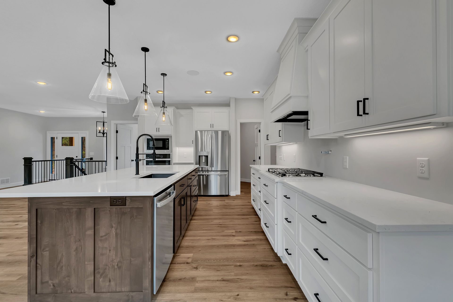 A kitchen with white cabinets , stainless steel appliances , and a large island.