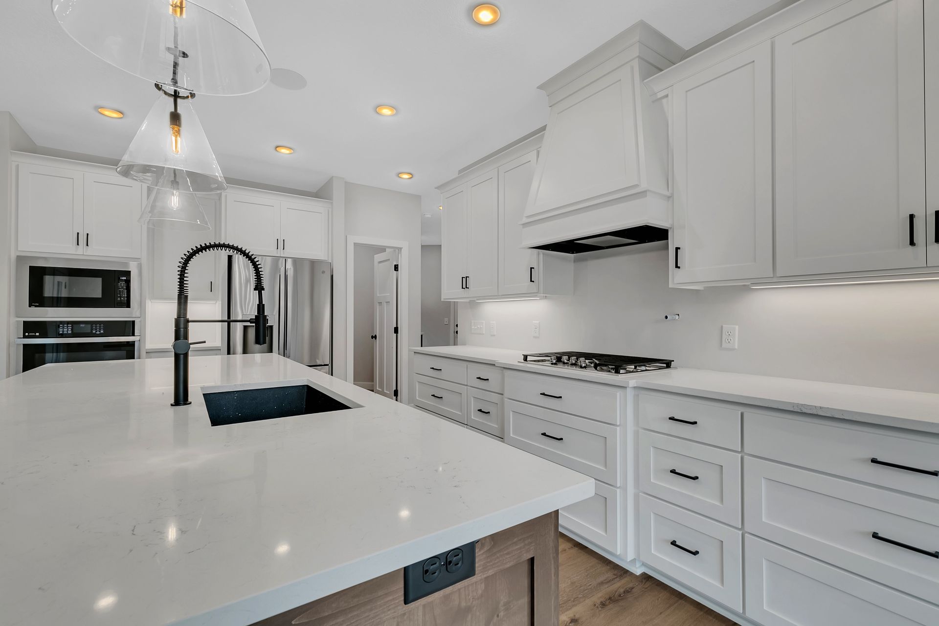 A kitchen with white cabinets , white counter tops , a sink , and a stove.