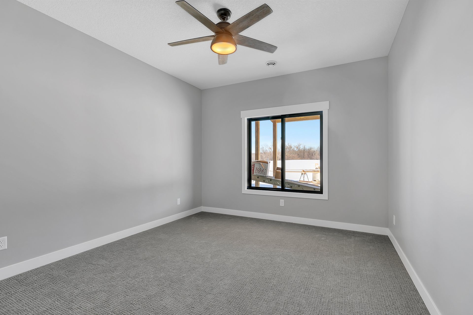 An empty bedroom with a ceiling fan and a window.