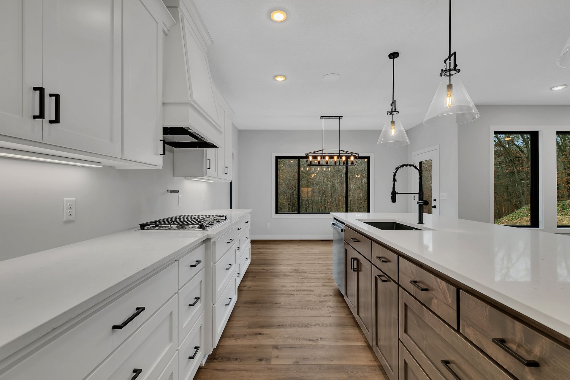 A kitchen with white cabinets and wooden floors and a large island in the middle.