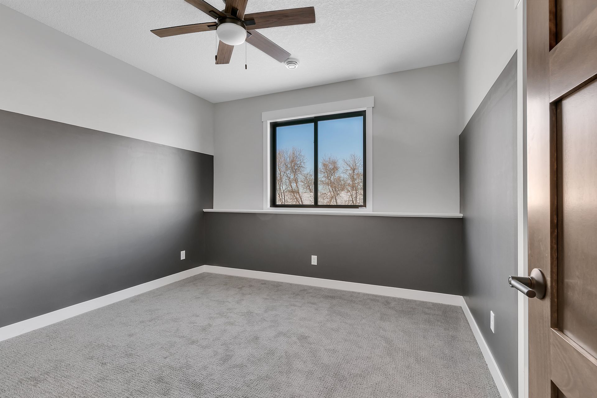 An empty bedroom with a ceiling fan and a window.