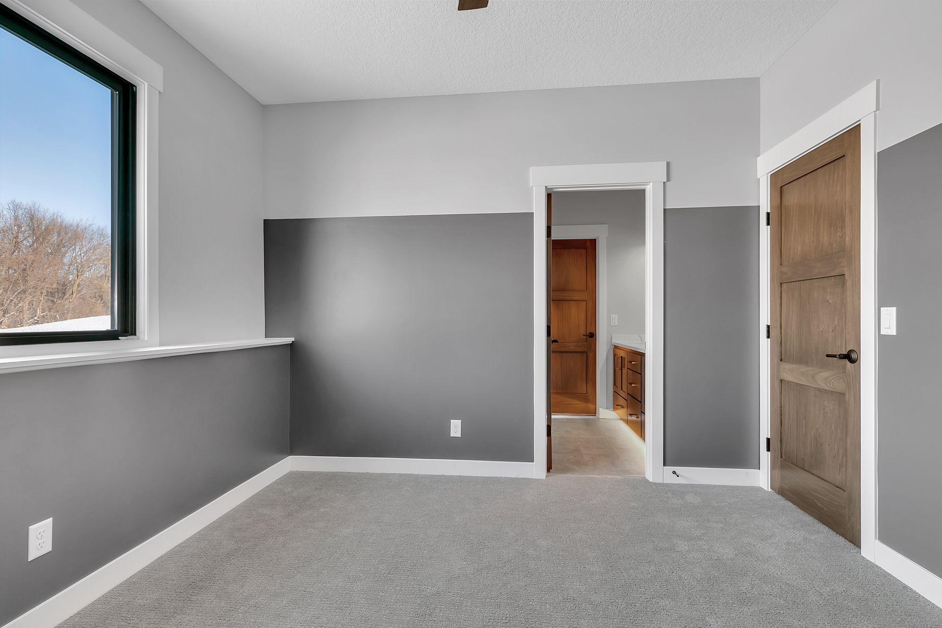 An empty bedroom with gray walls and a window.