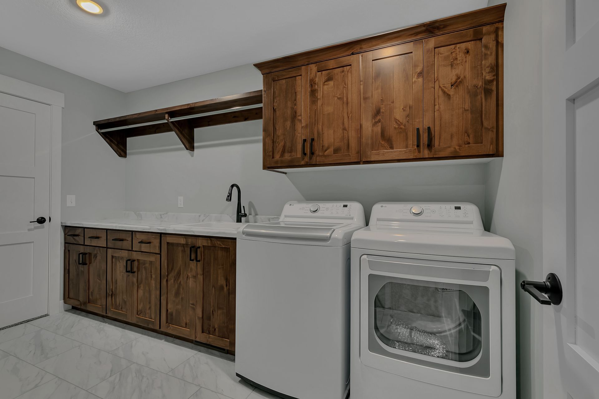 A laundry room with a washer and dryer and wooden cabinets.