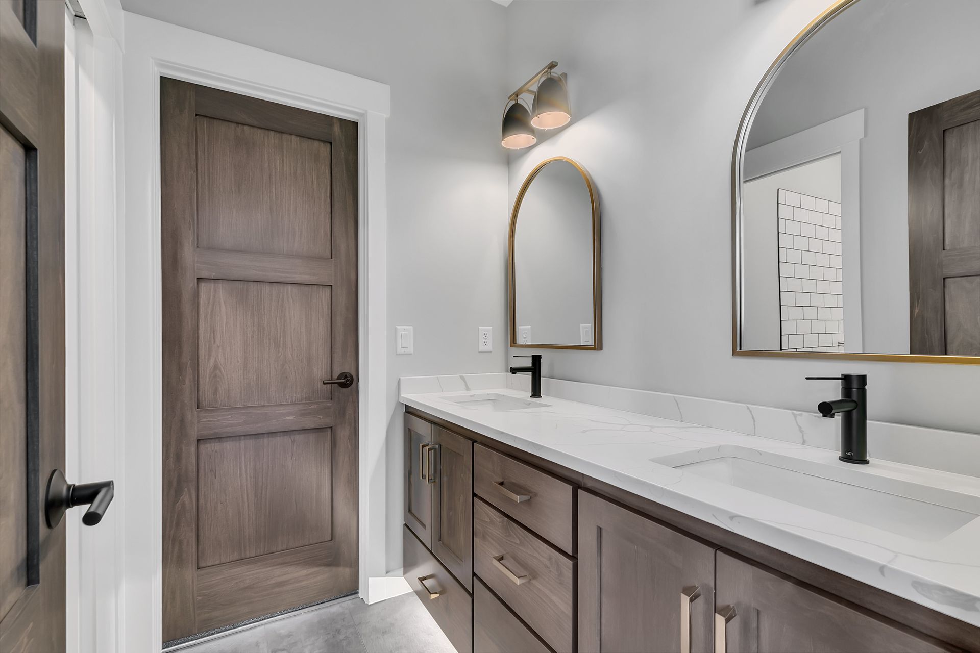 A bathroom with two sinks , a mirror and a door.