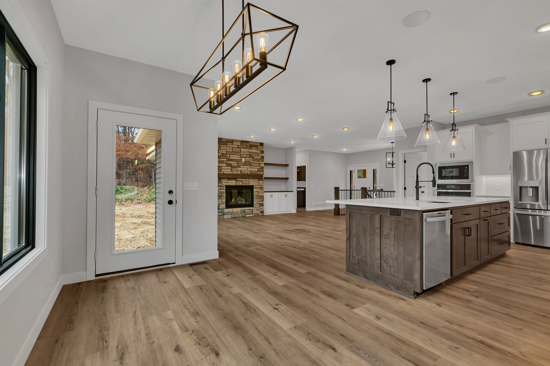 A kitchen with hardwood floors , stainless steel appliances , a large island and a fireplace.