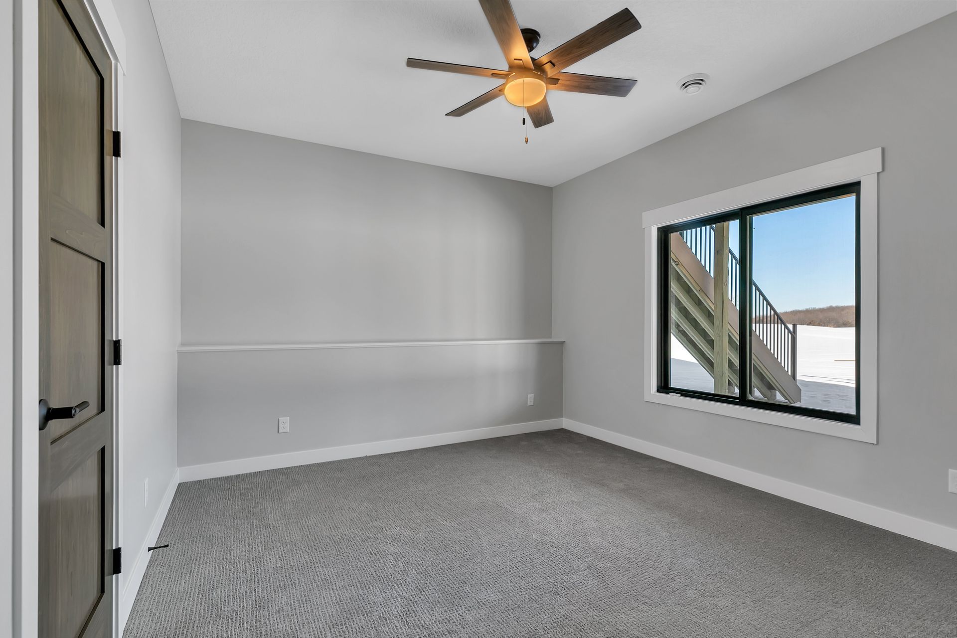 An empty room with a ceiling fan and a window.