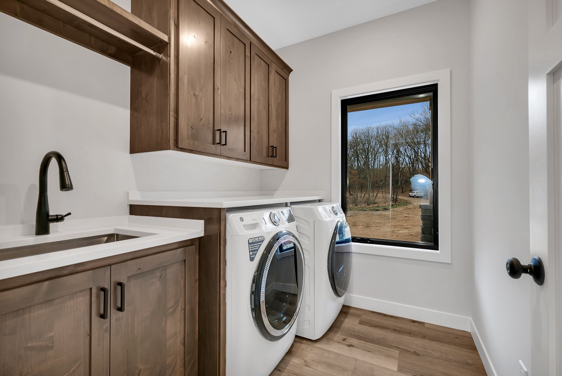 A laundry room with a washer and dryer , sink , and window.