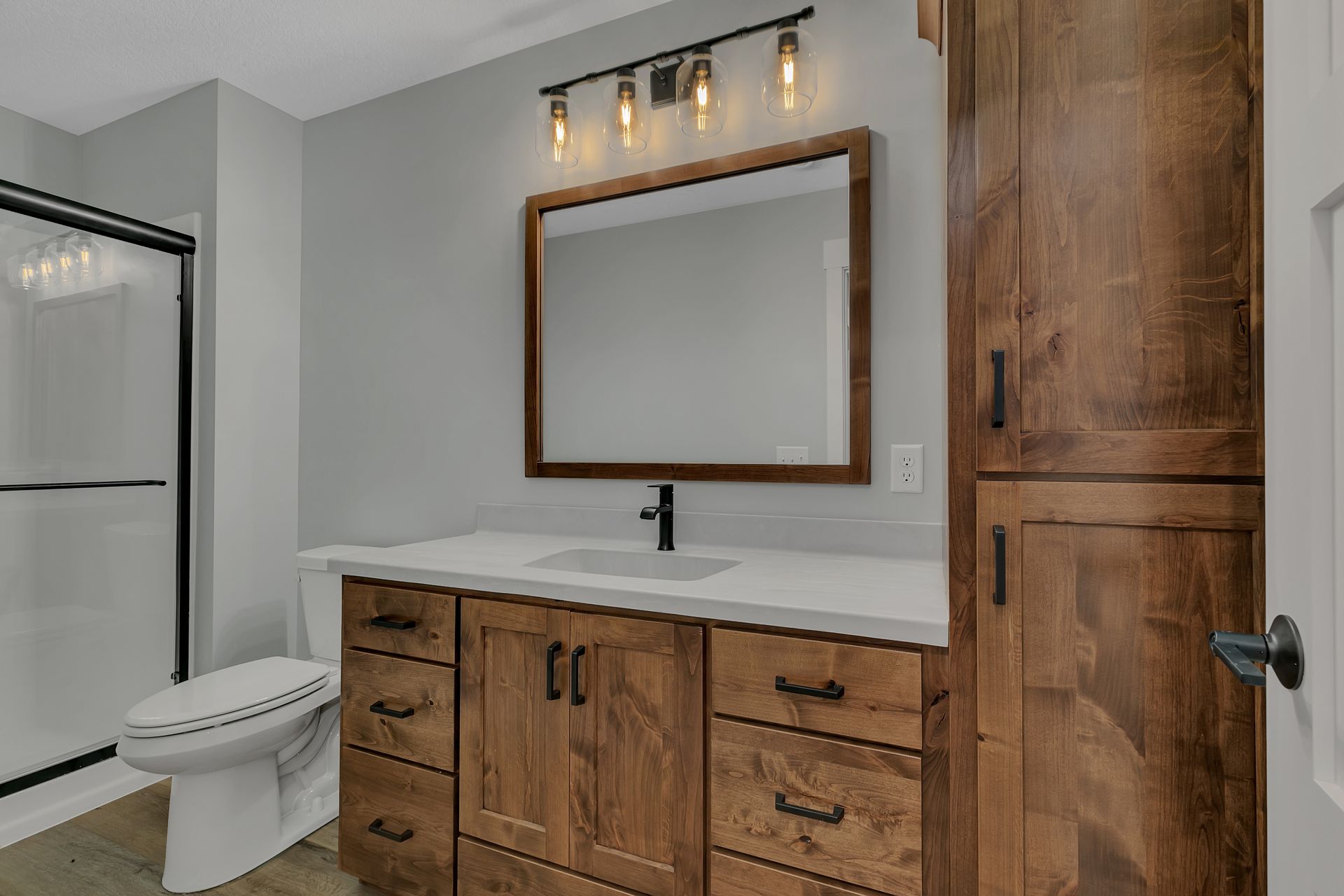 A bathroom with a toilet , sink , mirror and cabinets.