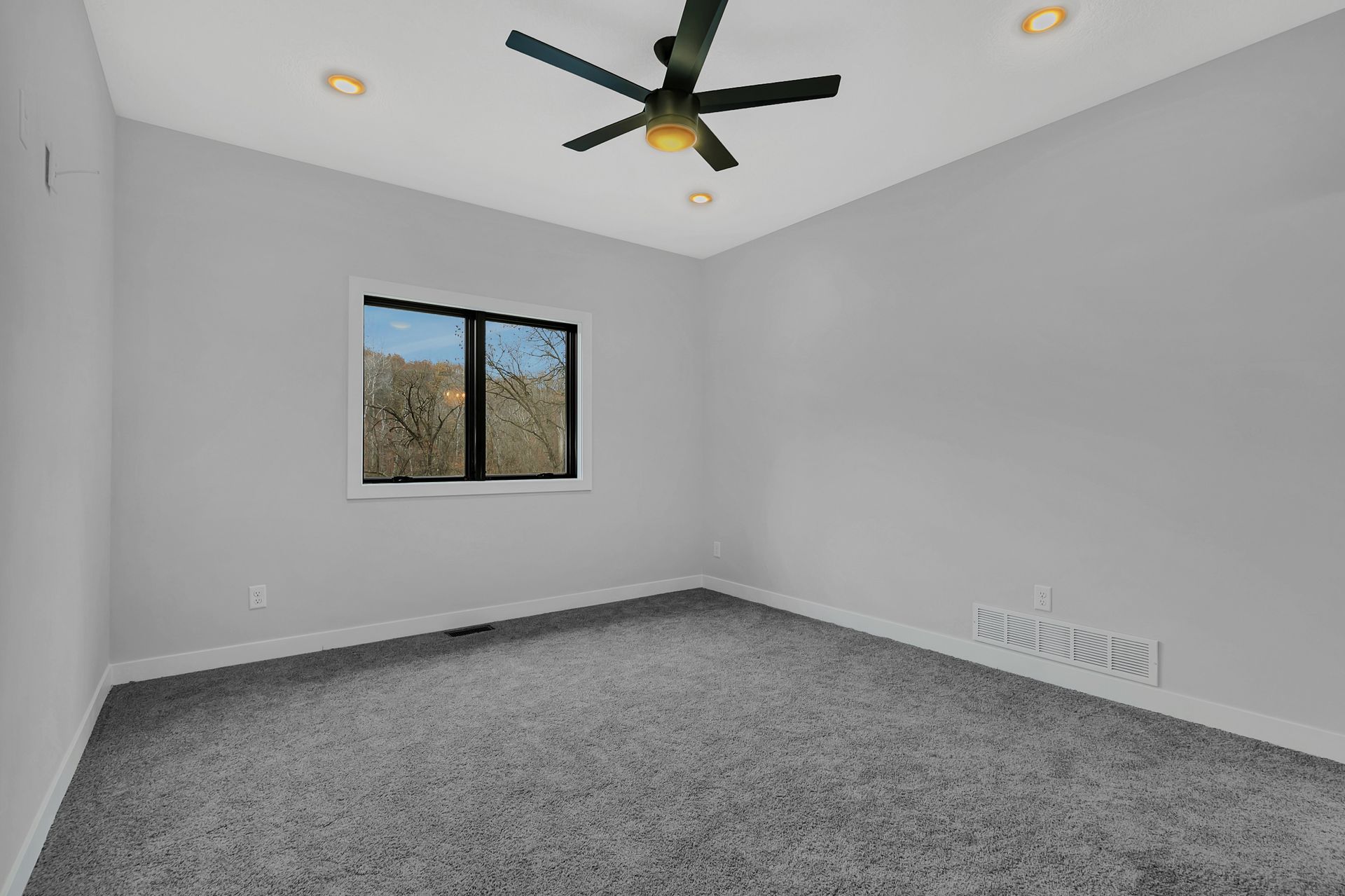 An empty bedroom with a ceiling fan and a window.
