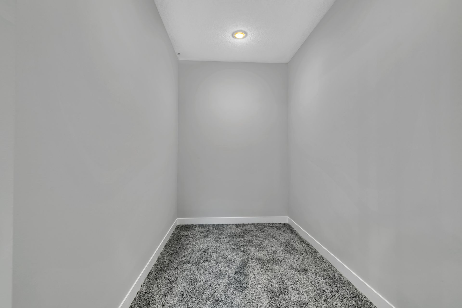 An empty room with gray walls and a gray carpet.