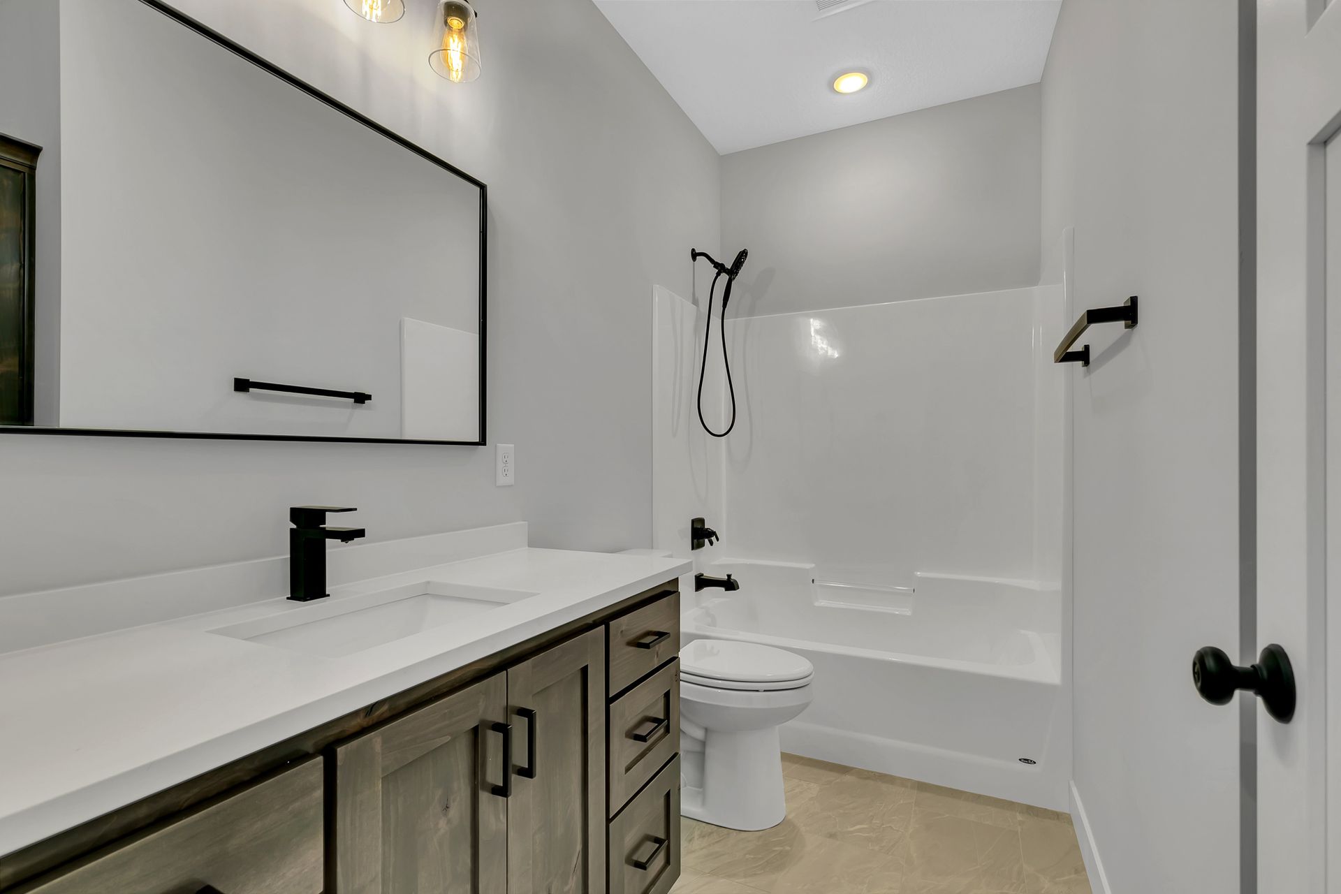 A bathroom with a sink , toilet , shower and mirror.