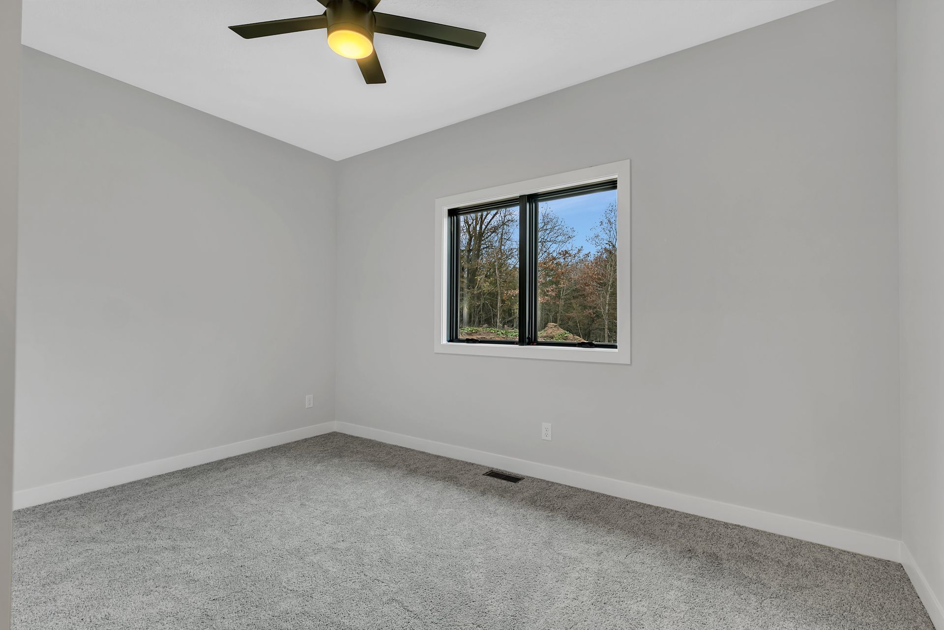 An empty bedroom with a ceiling fan and a window.
