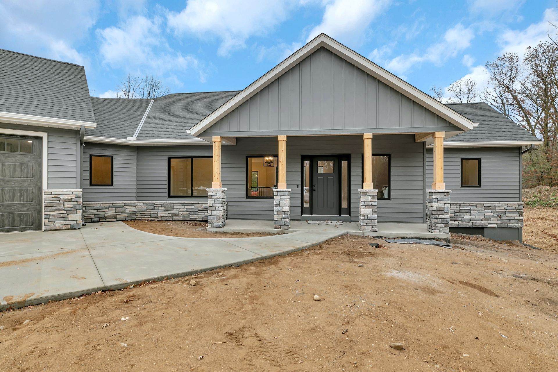 The front of a gray house with a porch and a garage.