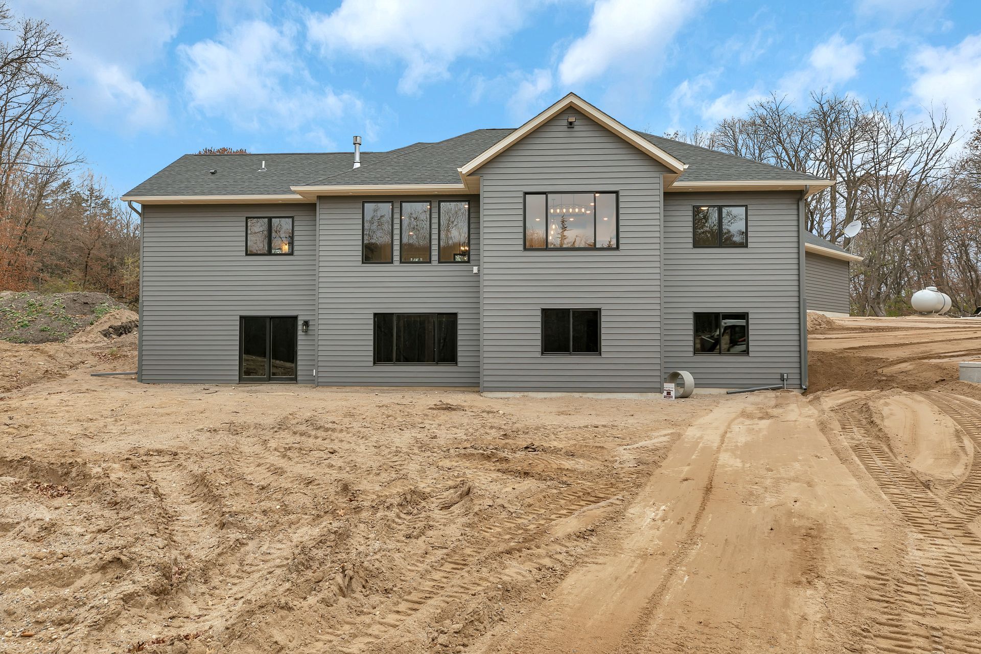 A large house is sitting in the middle of a dirt field.